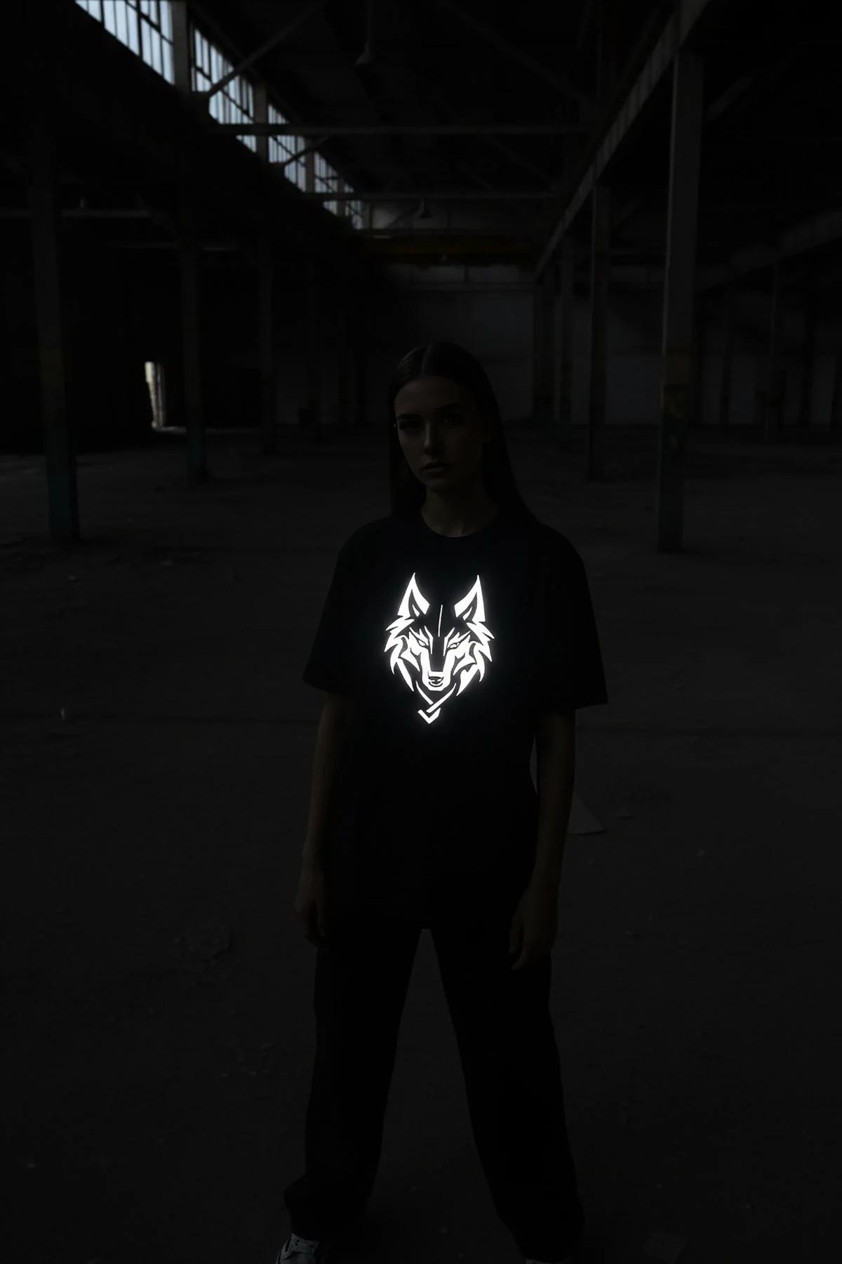 black oversize t-shirt with bright white reflective geometric wolf head front print glowing under camera flash