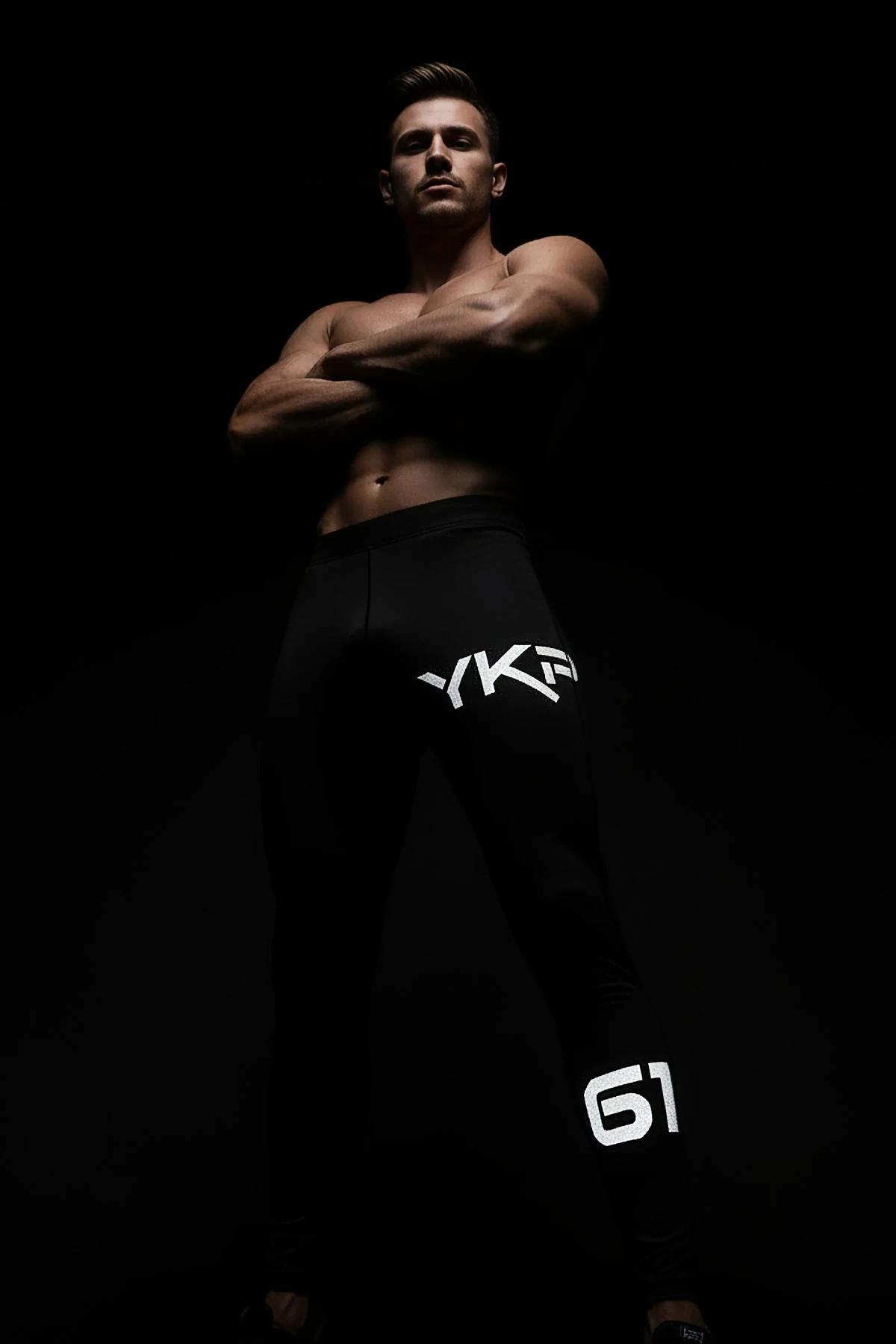 Full-length view of black athletic leggings with glowing 61 reflective number print on lower leg