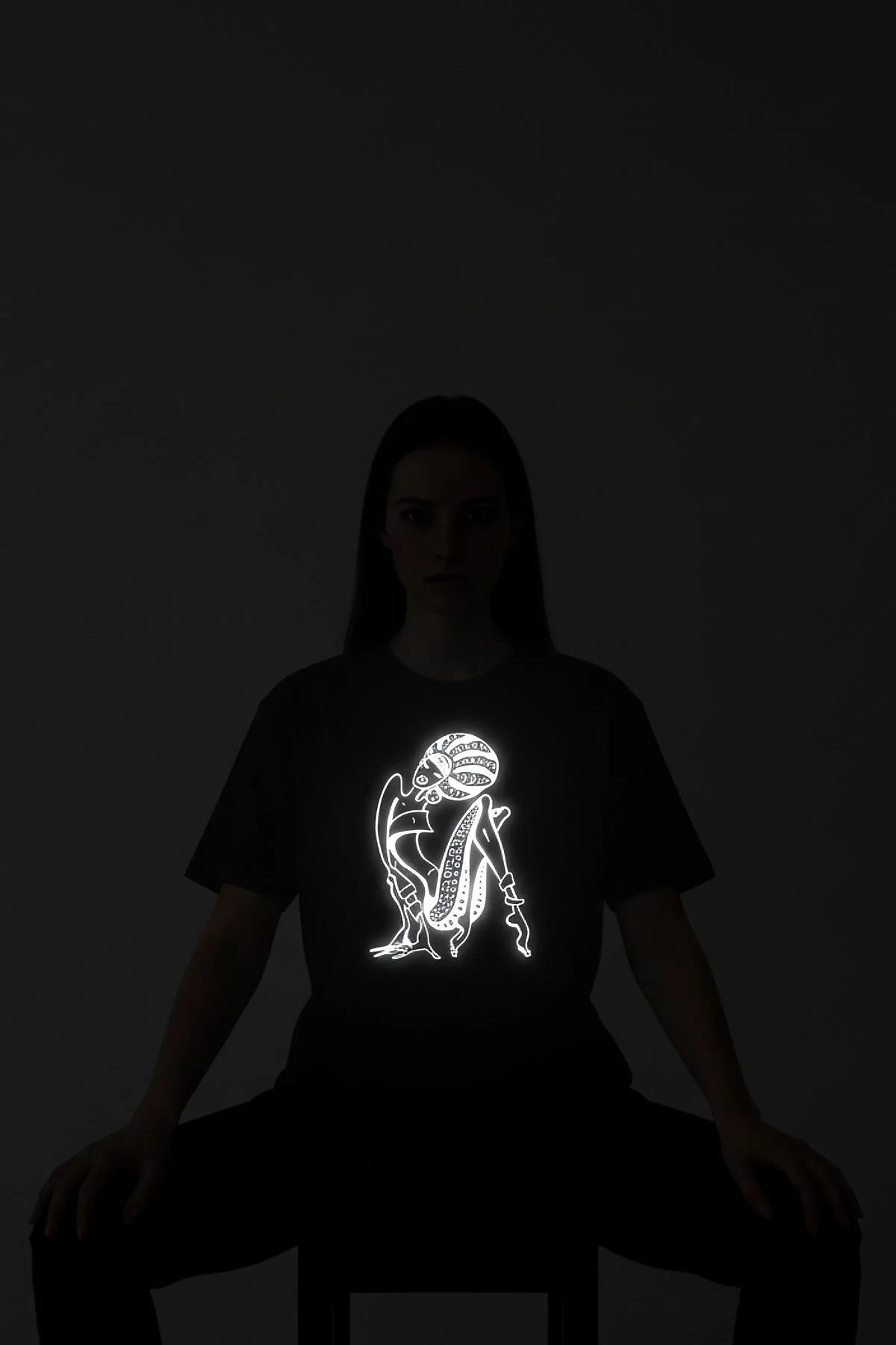 Reflective abstract female figure black oversize t-shirt glowing white under direct light, front print detail