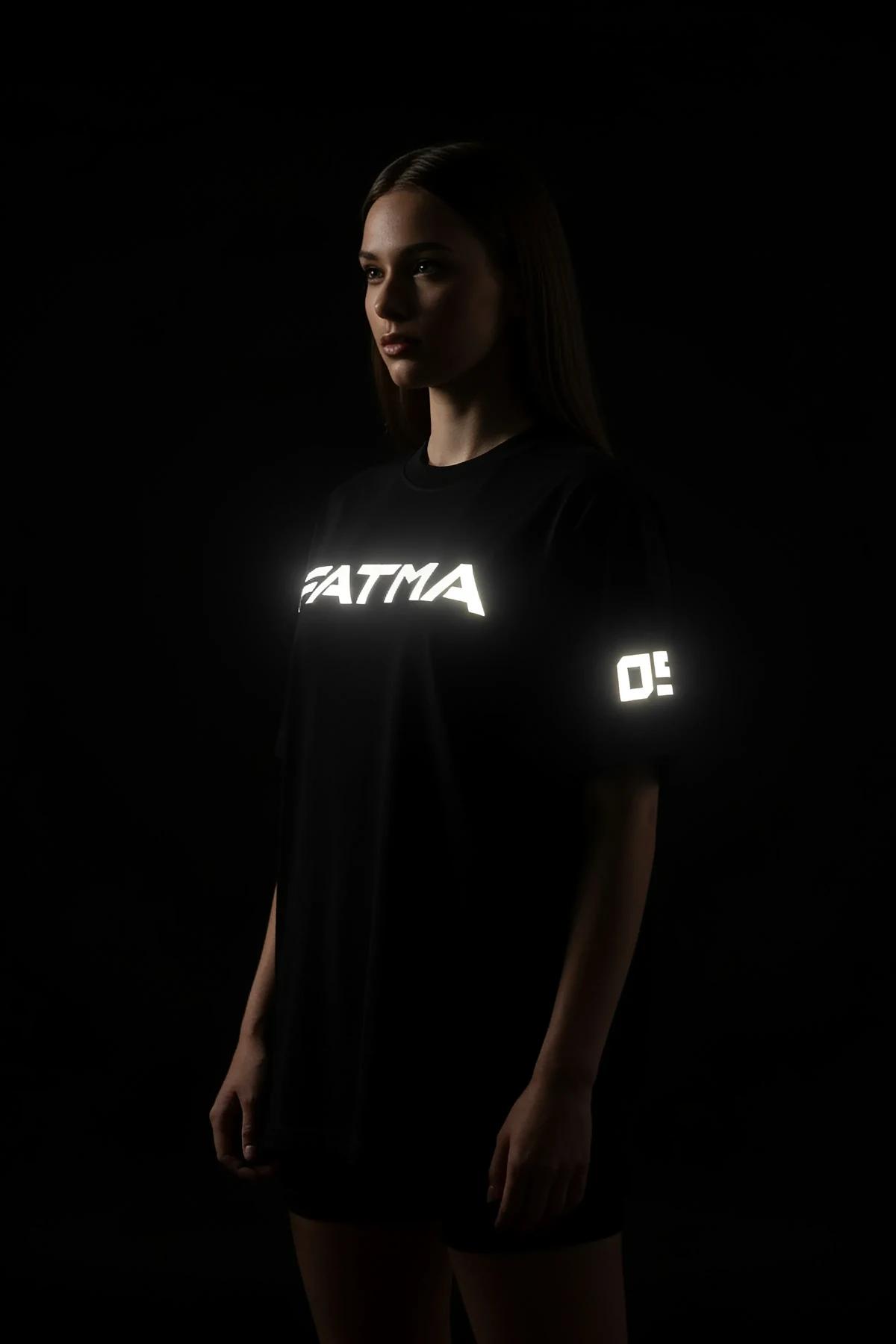 Front view of black heavyweight cotton oversize t-shirt with bright reflective chest print in condensed sans-serif font