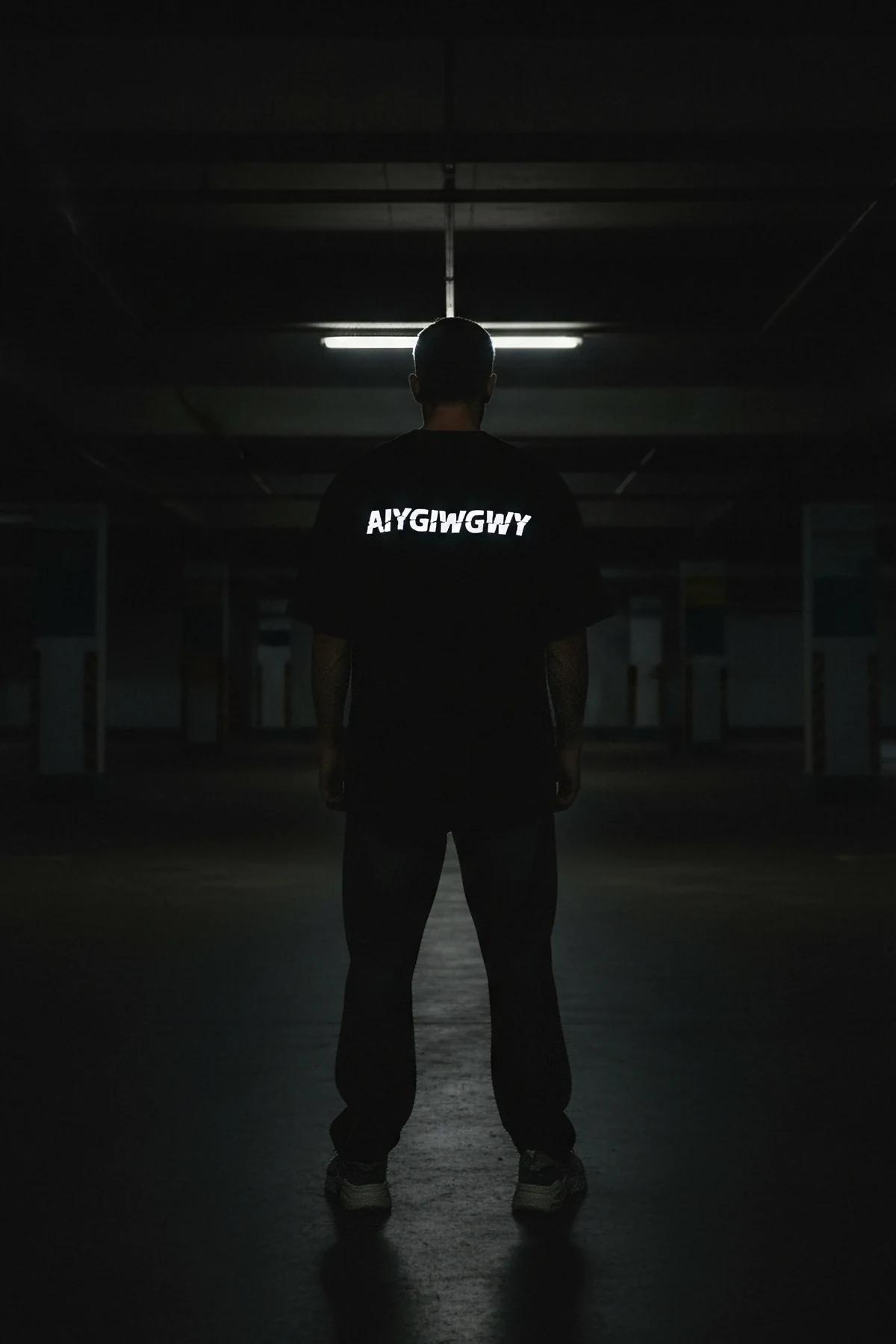 black oversize t-shirt with reflective chest slogan print shown from front in daylight matte finish