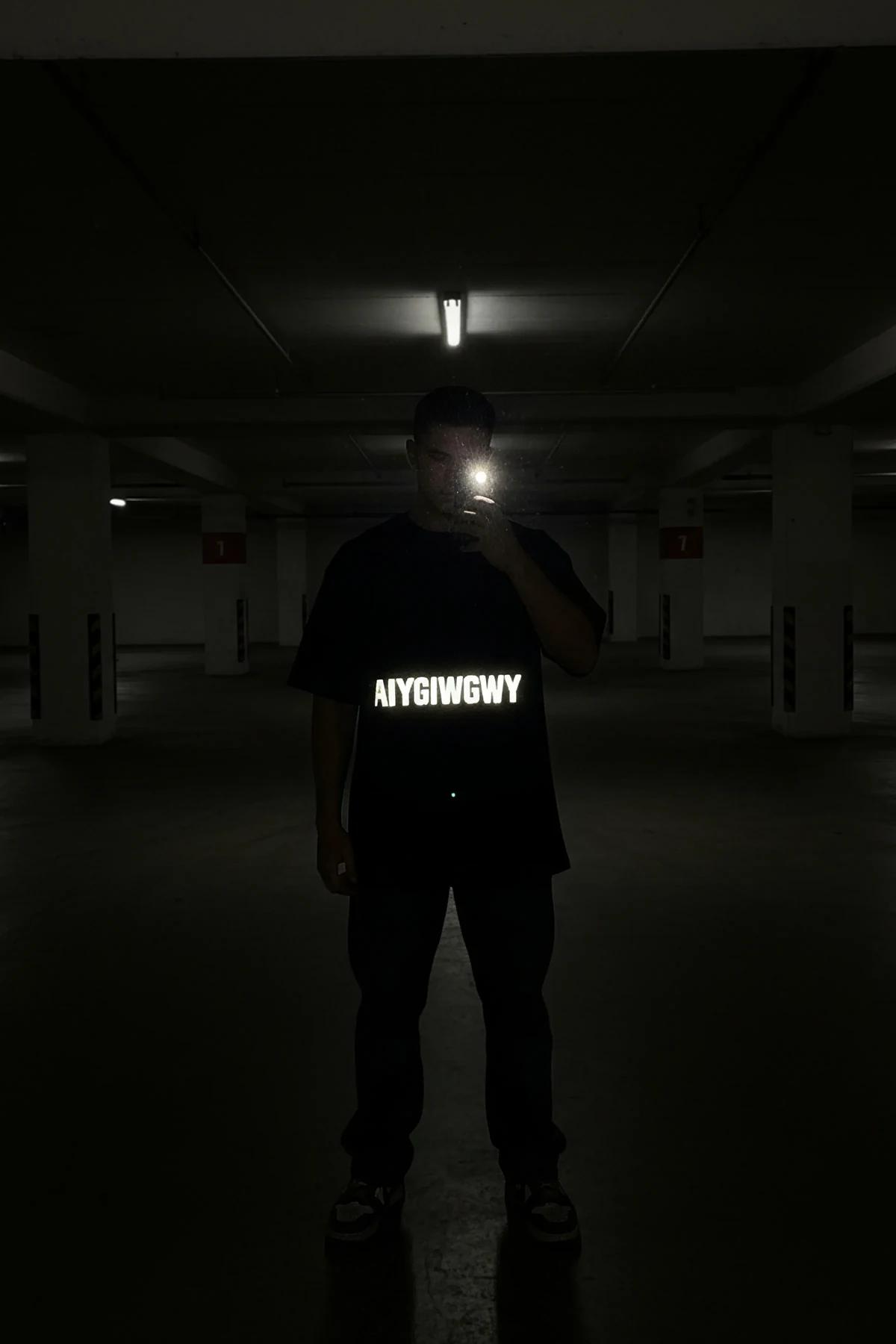 black oversize slogan tee worn with joggers showing mid-thigh hem length and relaxed shoulder drop