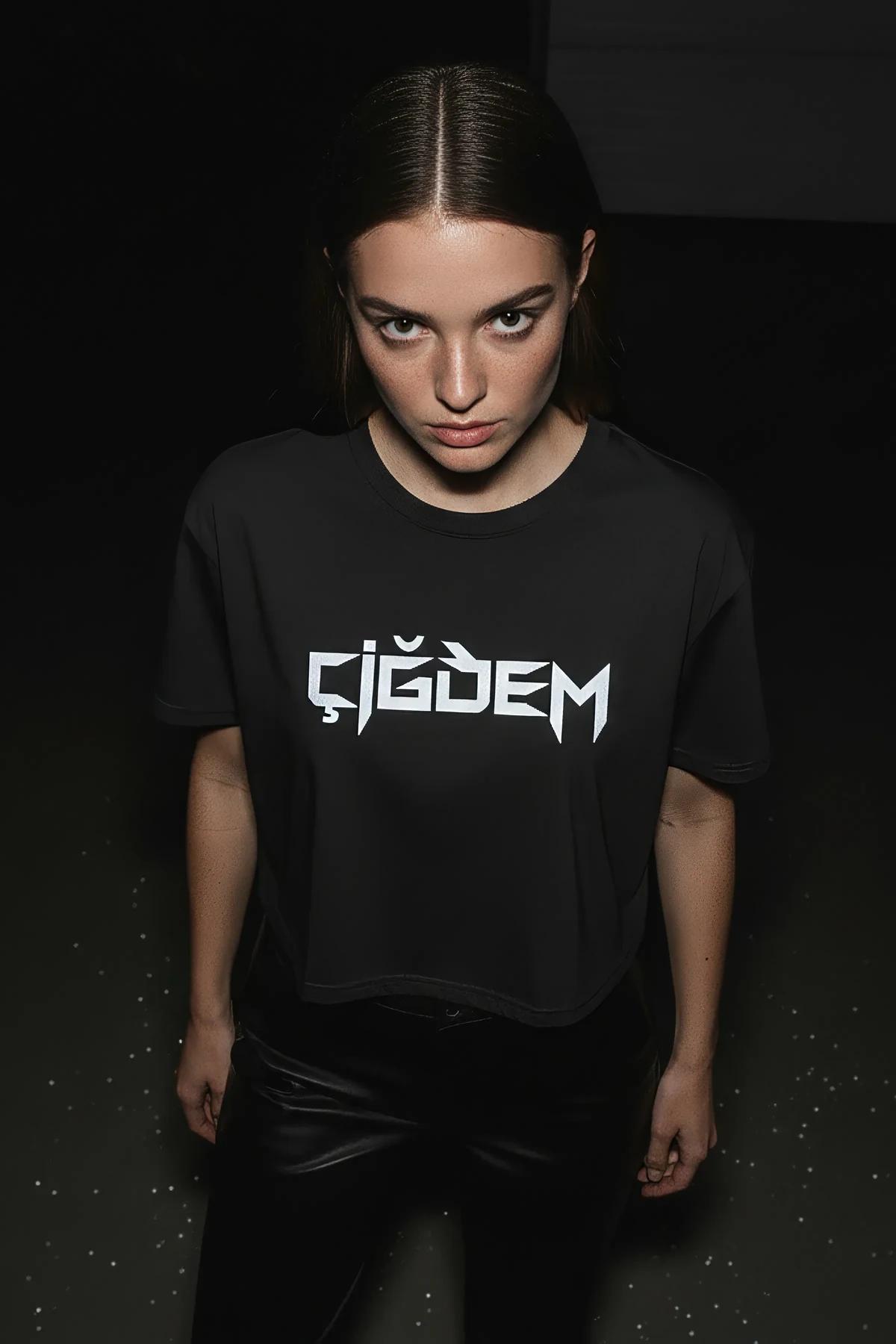 Close-up of reflective angular-typeface name print on black cotton crop tee under studio lighting