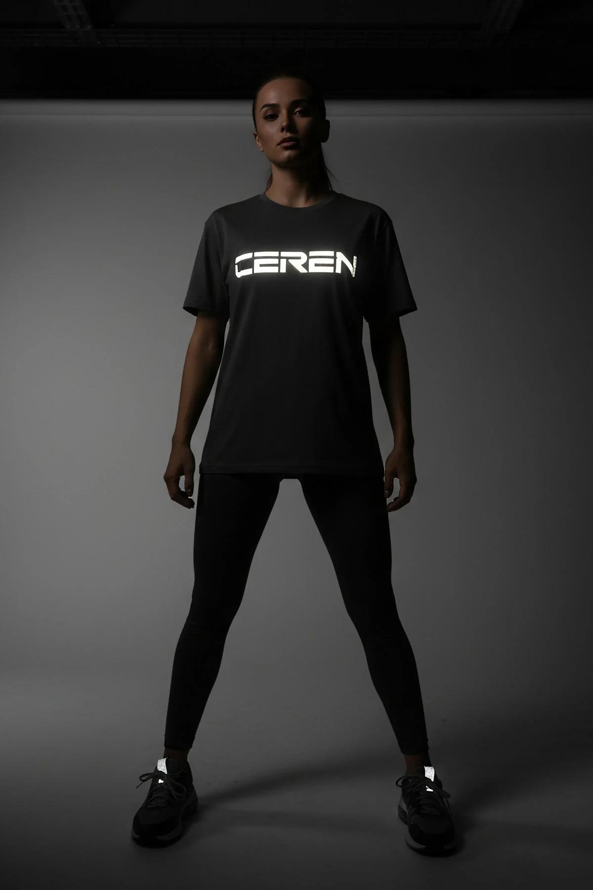 front view of black oversize cotton t-shirt with retroreflective graphic across chest in dark room