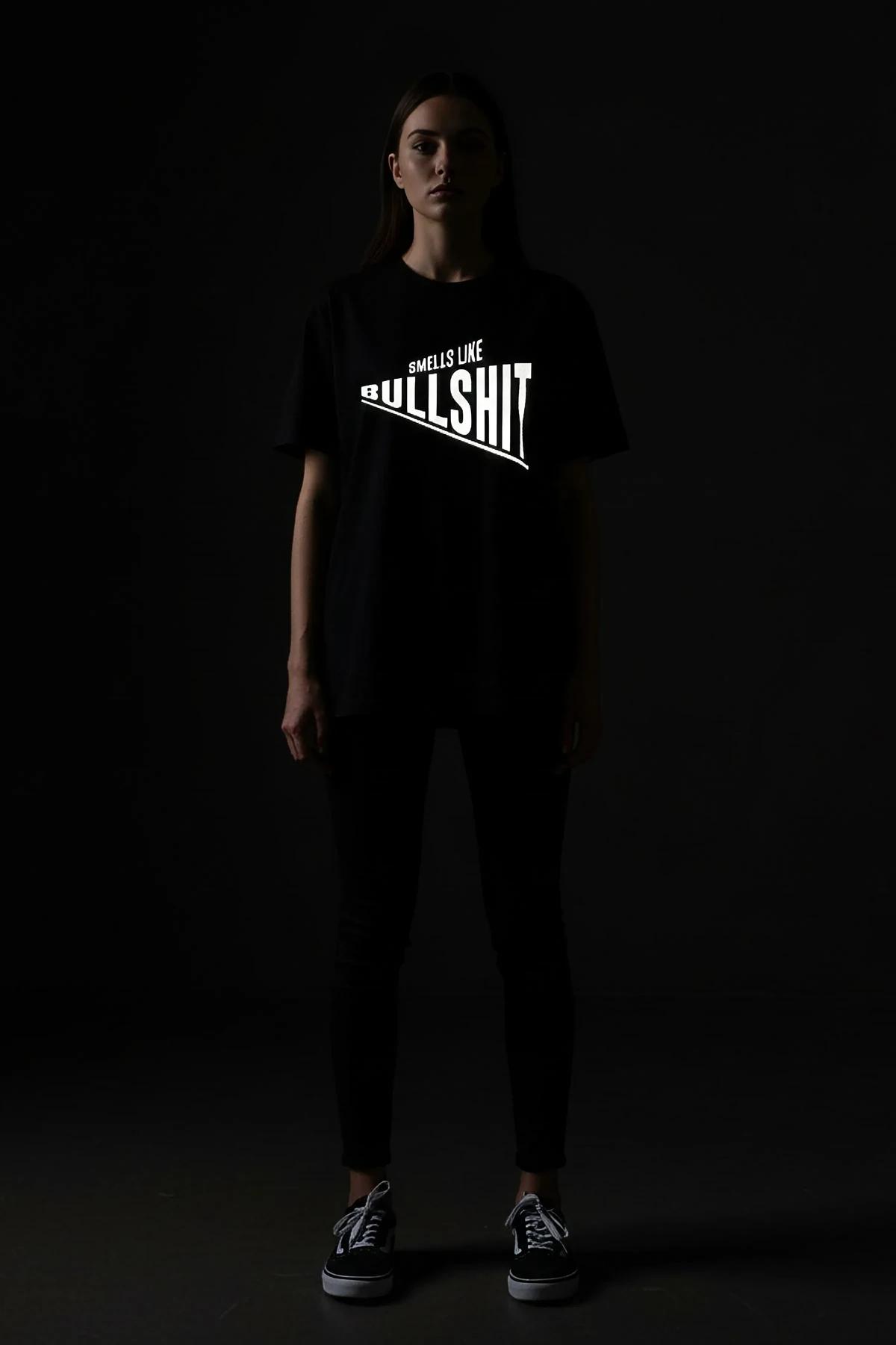 reflective print oversize black t-shirt bold white slogan glowing under flash dark studio shot