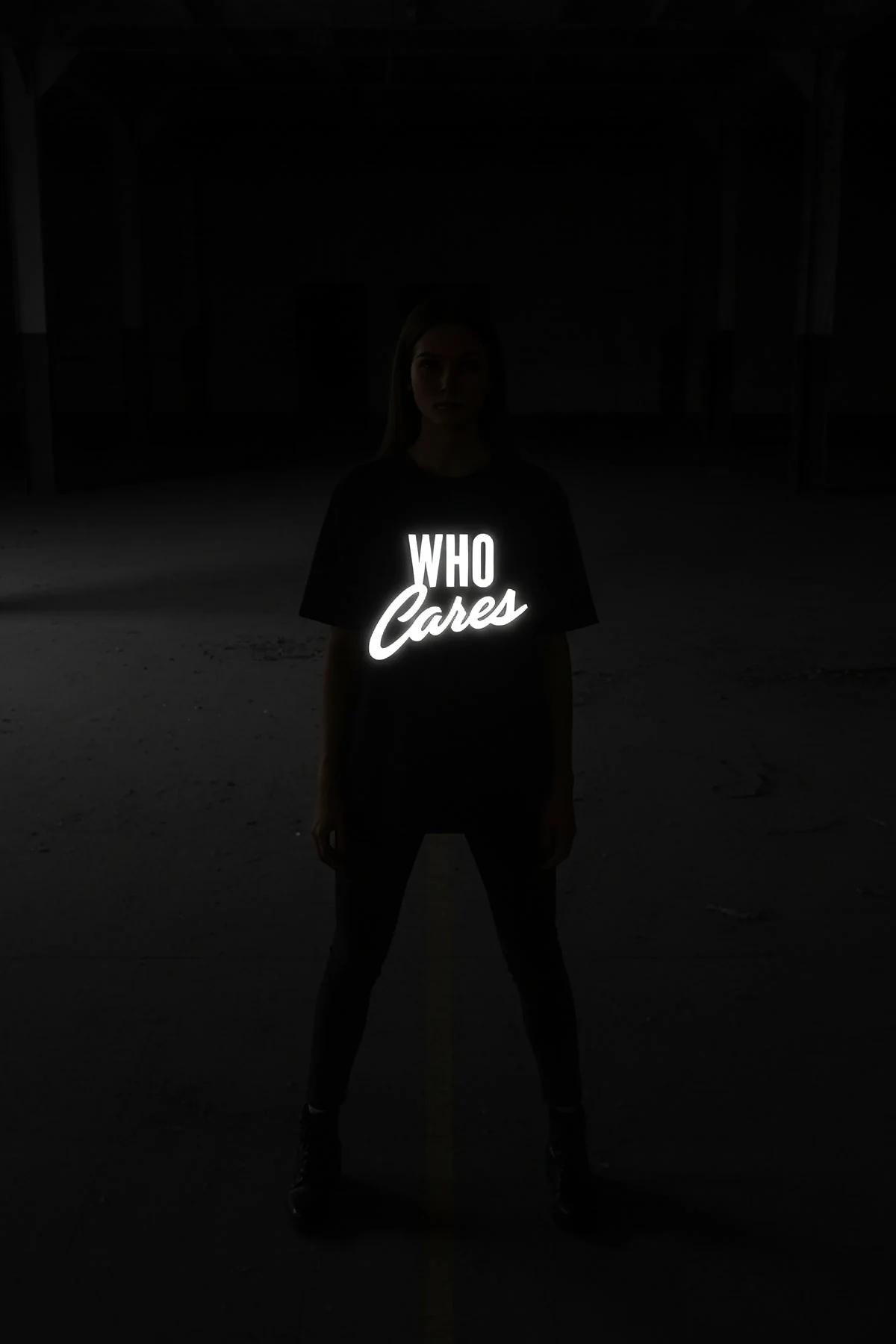 black oversize t-shirt with bright white reflective WHO Cares front print glowing in dark