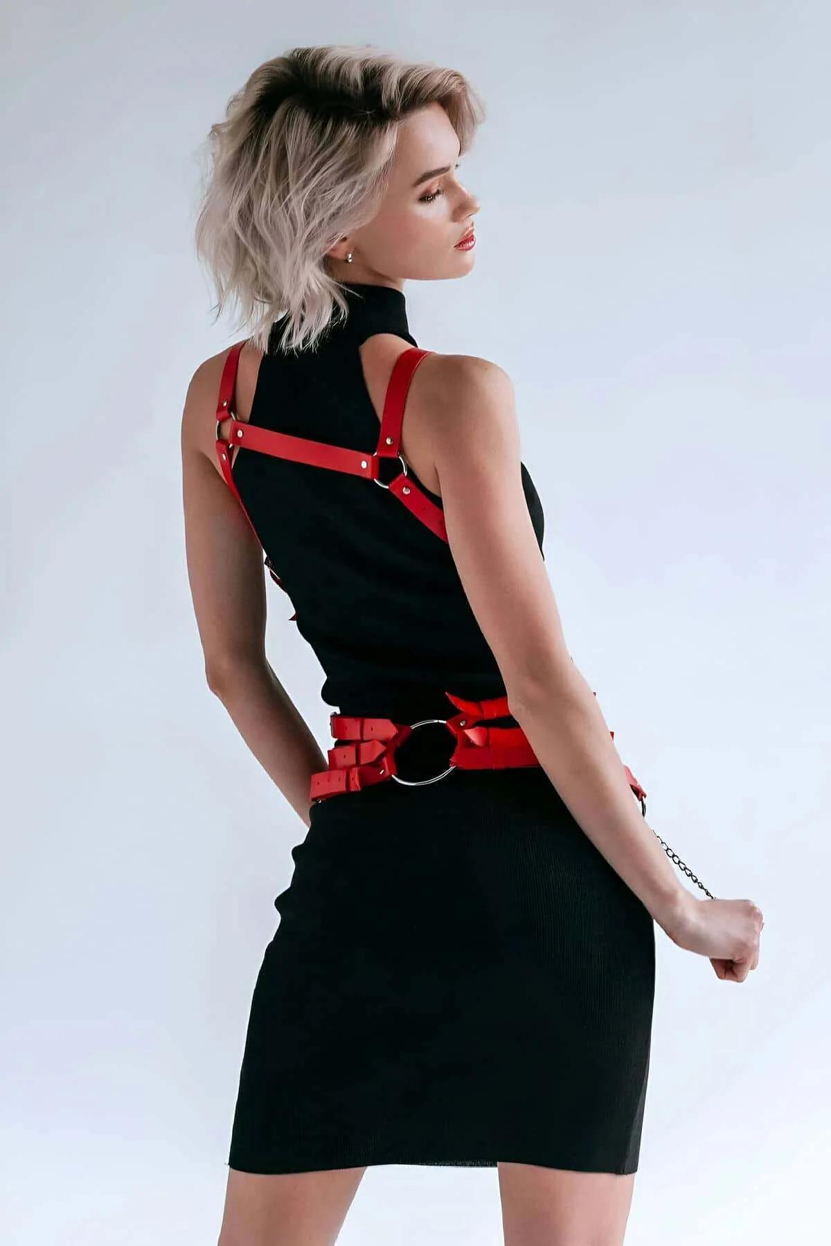 Adjustable shoulder straps of red PU leather body harness with silver buckle closures at back