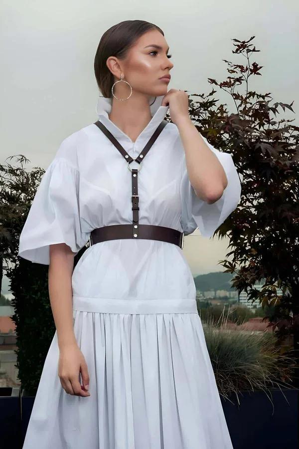 Espresso brown faux leather chest harness with wide waist belt and silver stud hardware worn over white midi dress