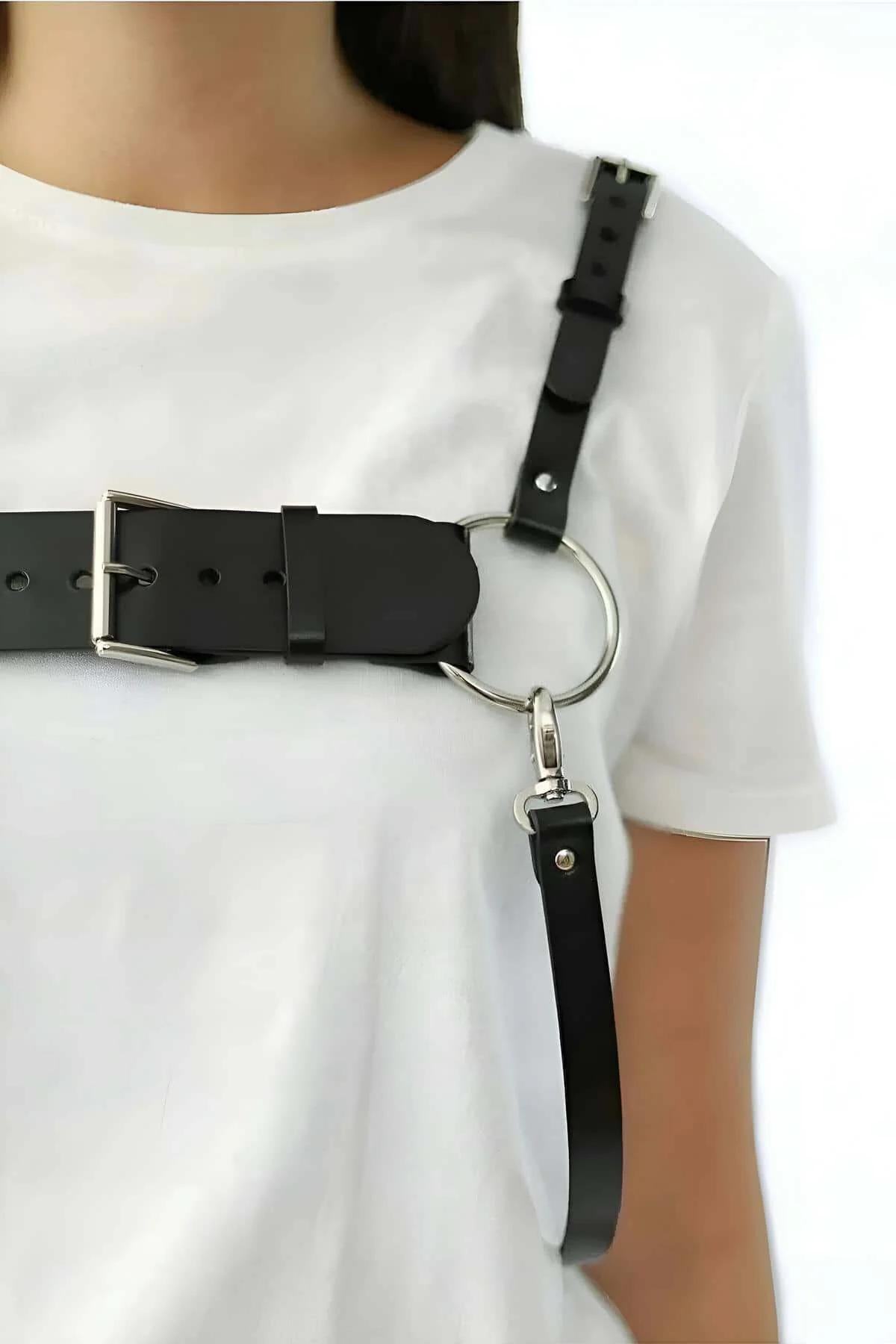 black chest harness with dual O-rings layered over a fitted white t-shirt and high-waist jeans