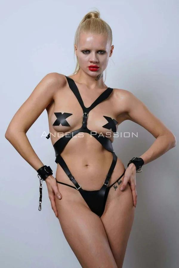 Black vegan leather full body harness with cross-chest X-straps, silver buckles, hip bands, and matching wrist cuffs with cha