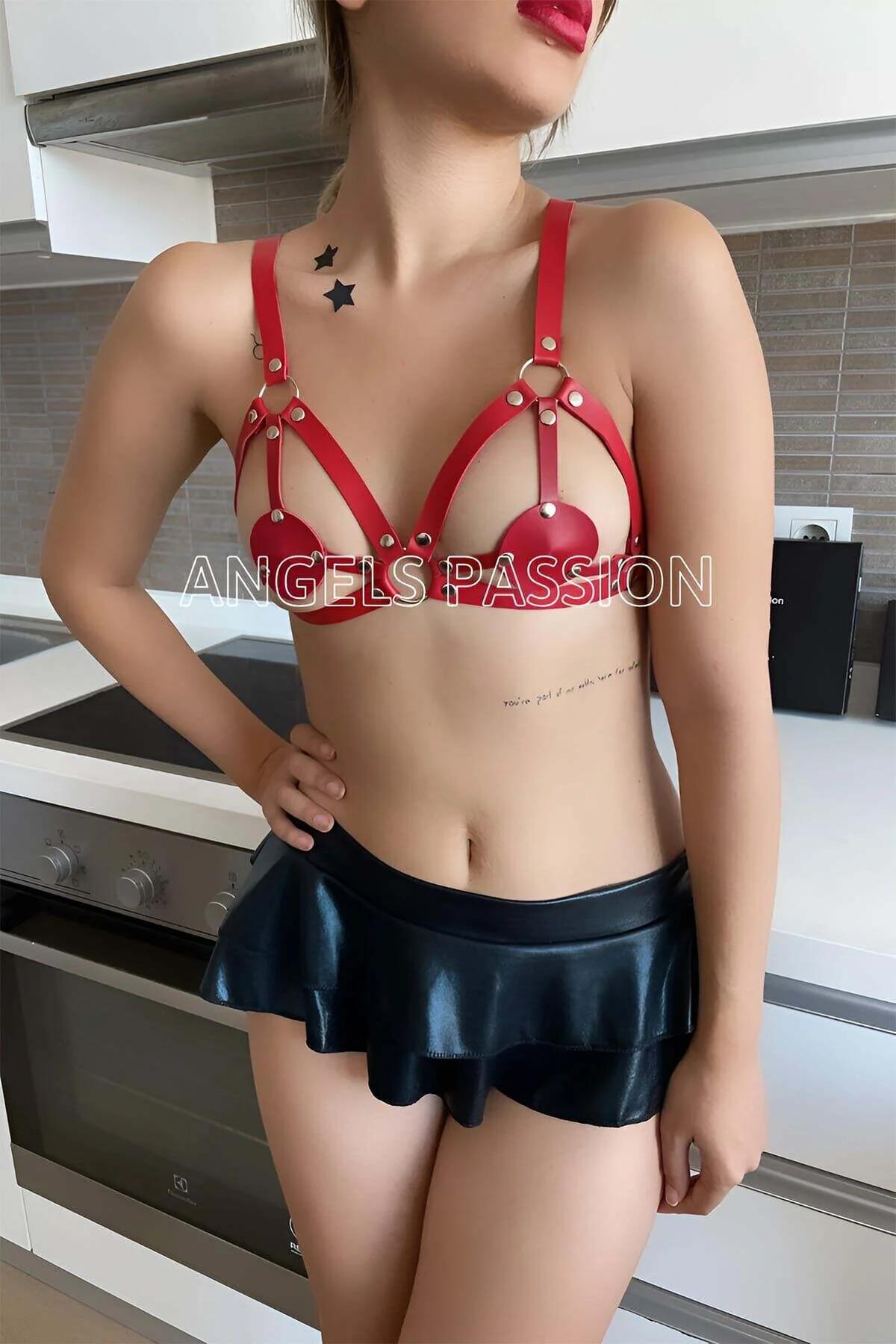 Close-up of gold-tone O-ring and dome rivet detail on red faux leather harness bra straps