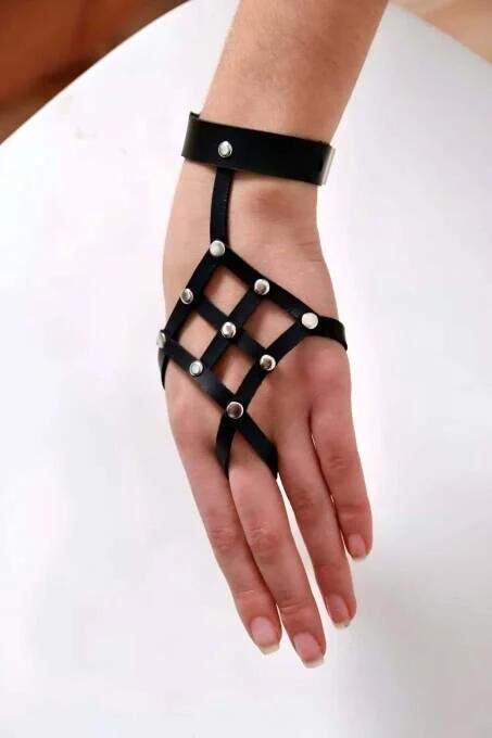 Black faux leather hand harness with diamond-grid cage and silver dome studs, top-down view