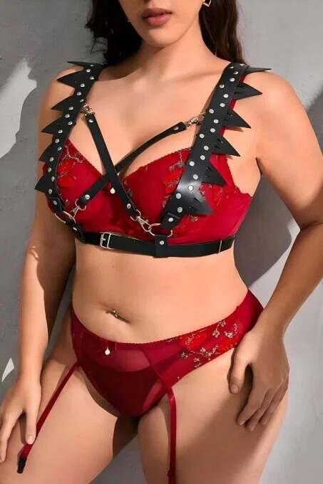 Close-up of black faux leather spike-cut trim and silver dome studs on chest harness shoulder strap