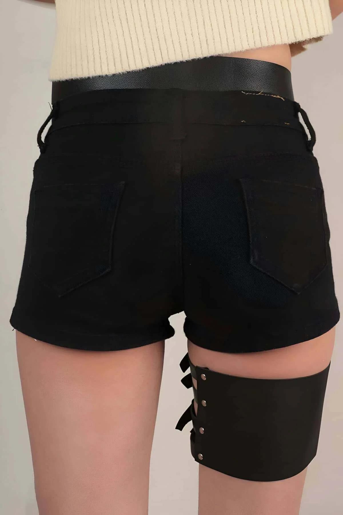 Full front view of black faux leather garter harness styled over black high-waisted shorts