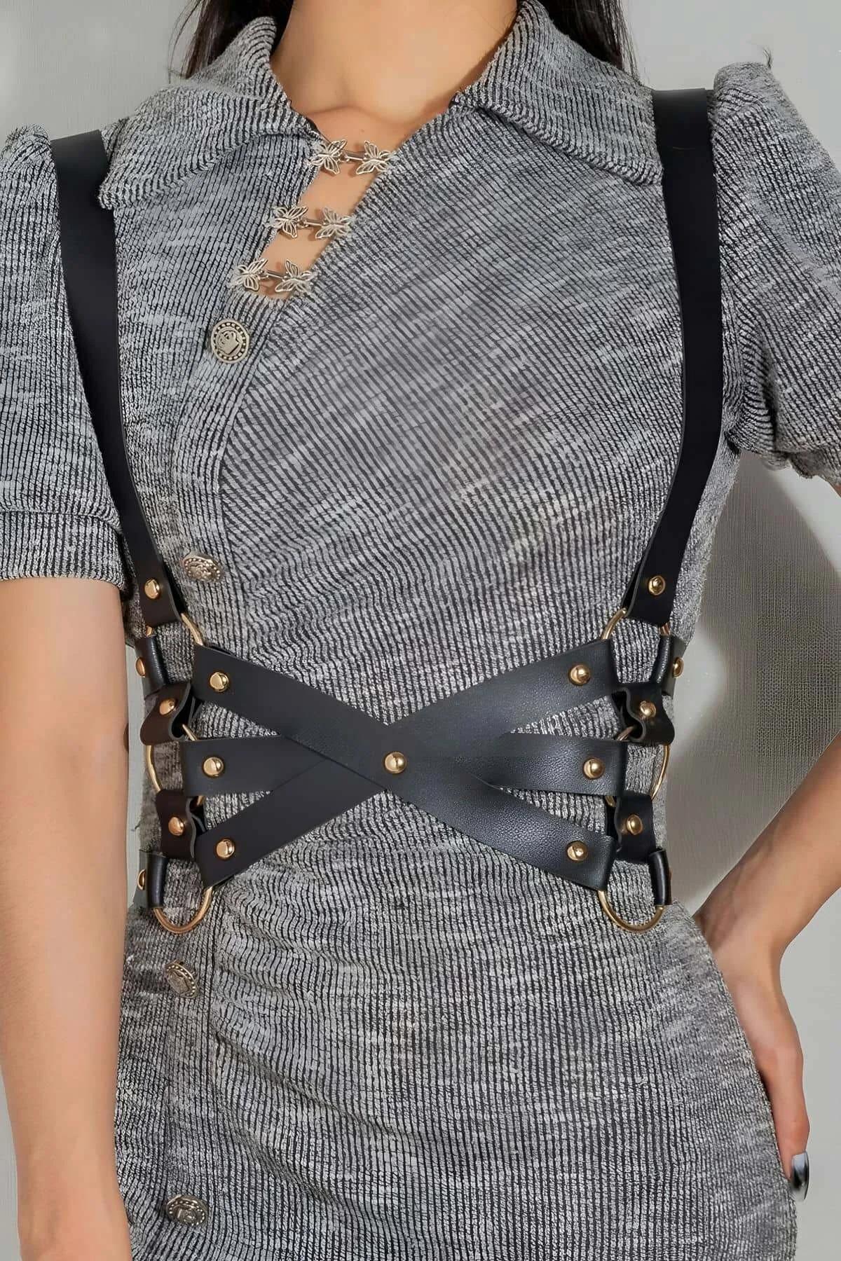 crisscross front panel detail of black faux leather body harness with gold buckle adjusters