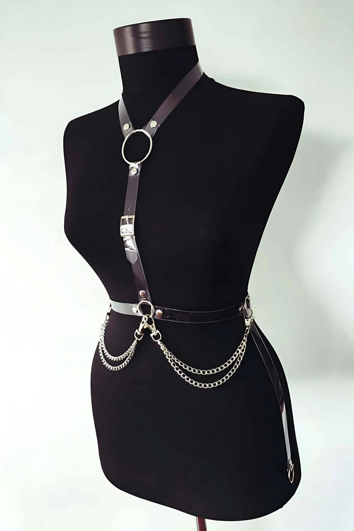 Close-up of silver O-ring and curb-link chains on black patent leather waist belt