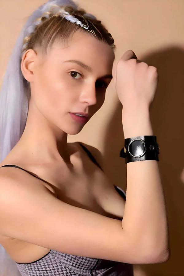 black faux leather wrist cuff with silver dome stud worn on wrist snap-button closure 4 cm wide band