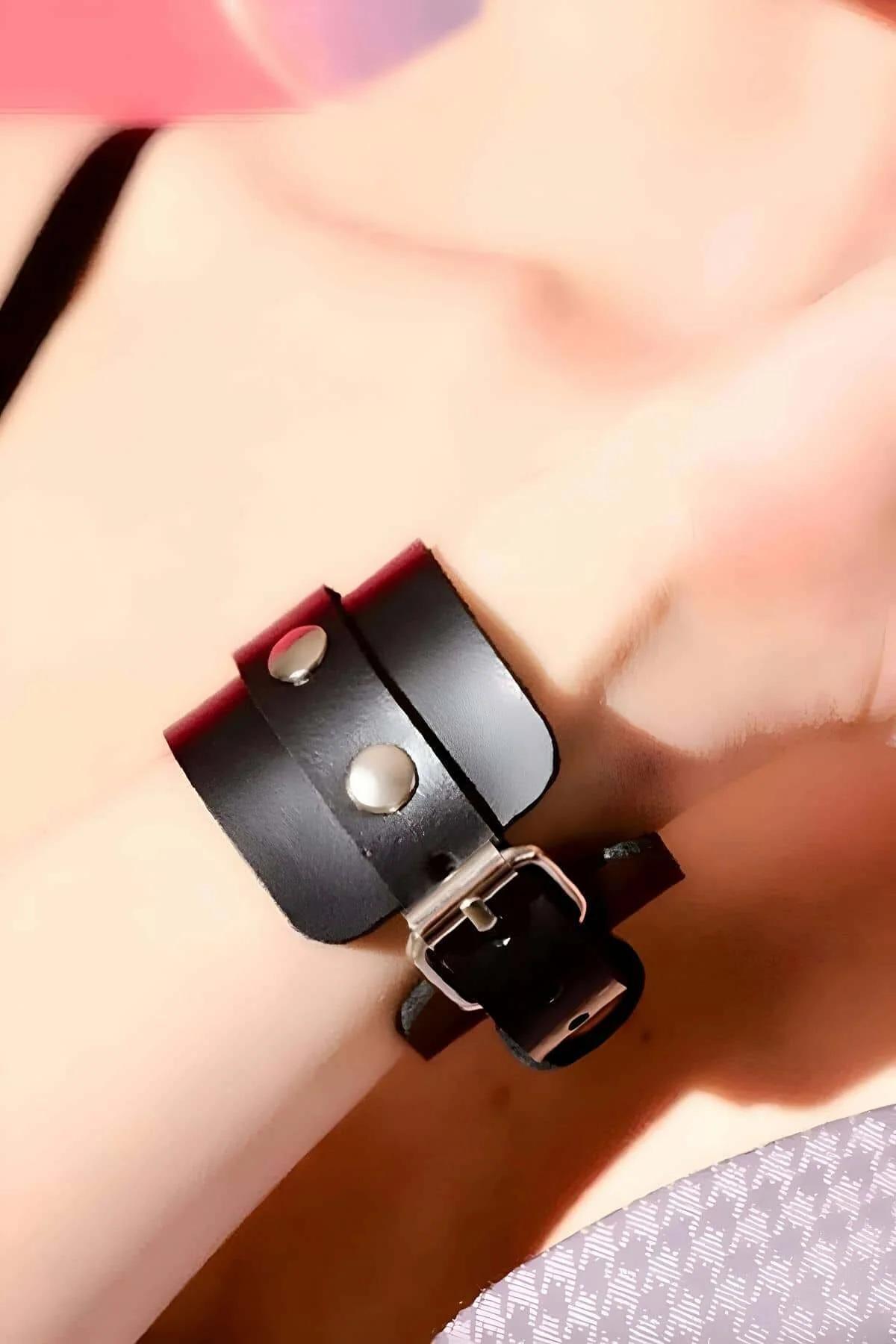 close-up of silver dome stud on black PU leather wrist cuff with snap closure detail