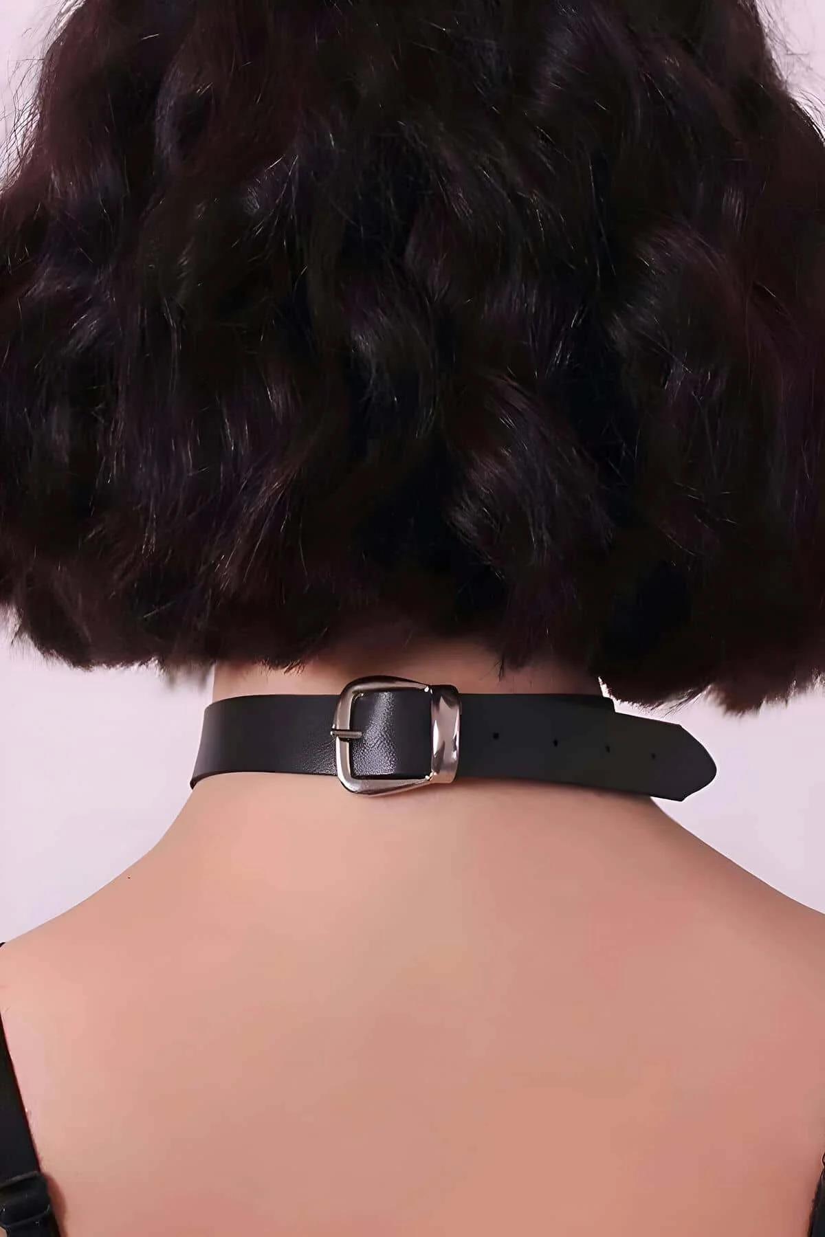 Black vegan leather choker worn at neck with tassel chain falling to mid-chest over dark mesh top
