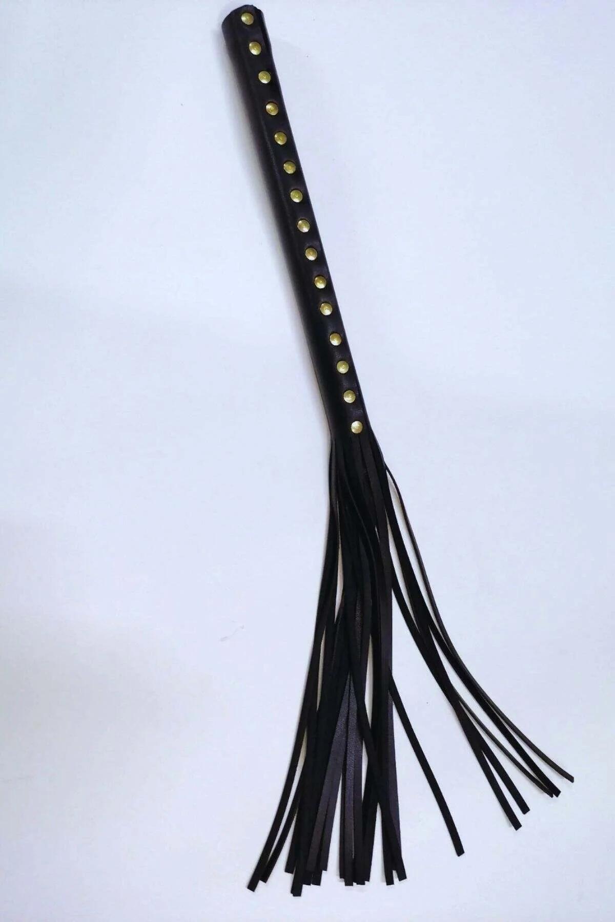 black faux leather studded tassel whip accessory with gold-tone metal studs along handle and long flat fringe