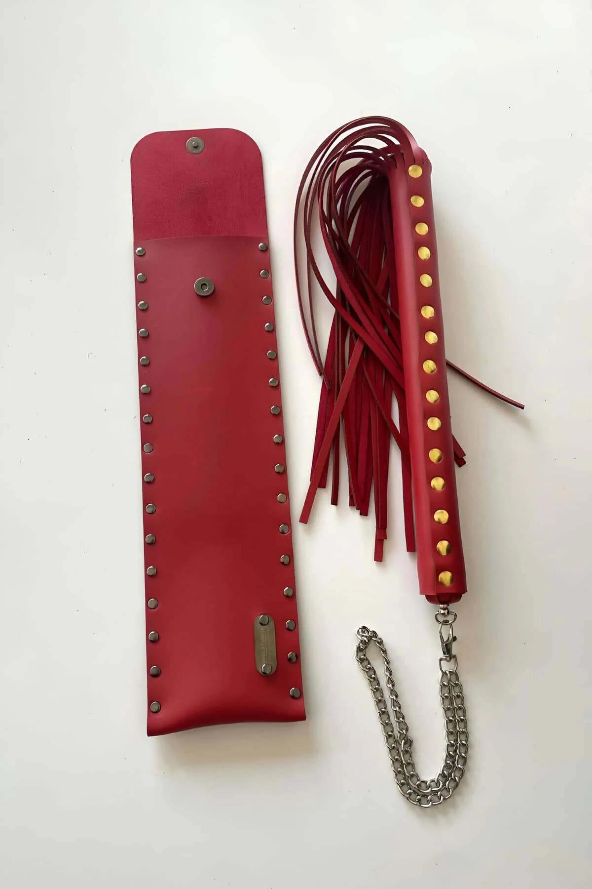 Studded red faux leather carry pouch with snap clasp closure shown open on grass background