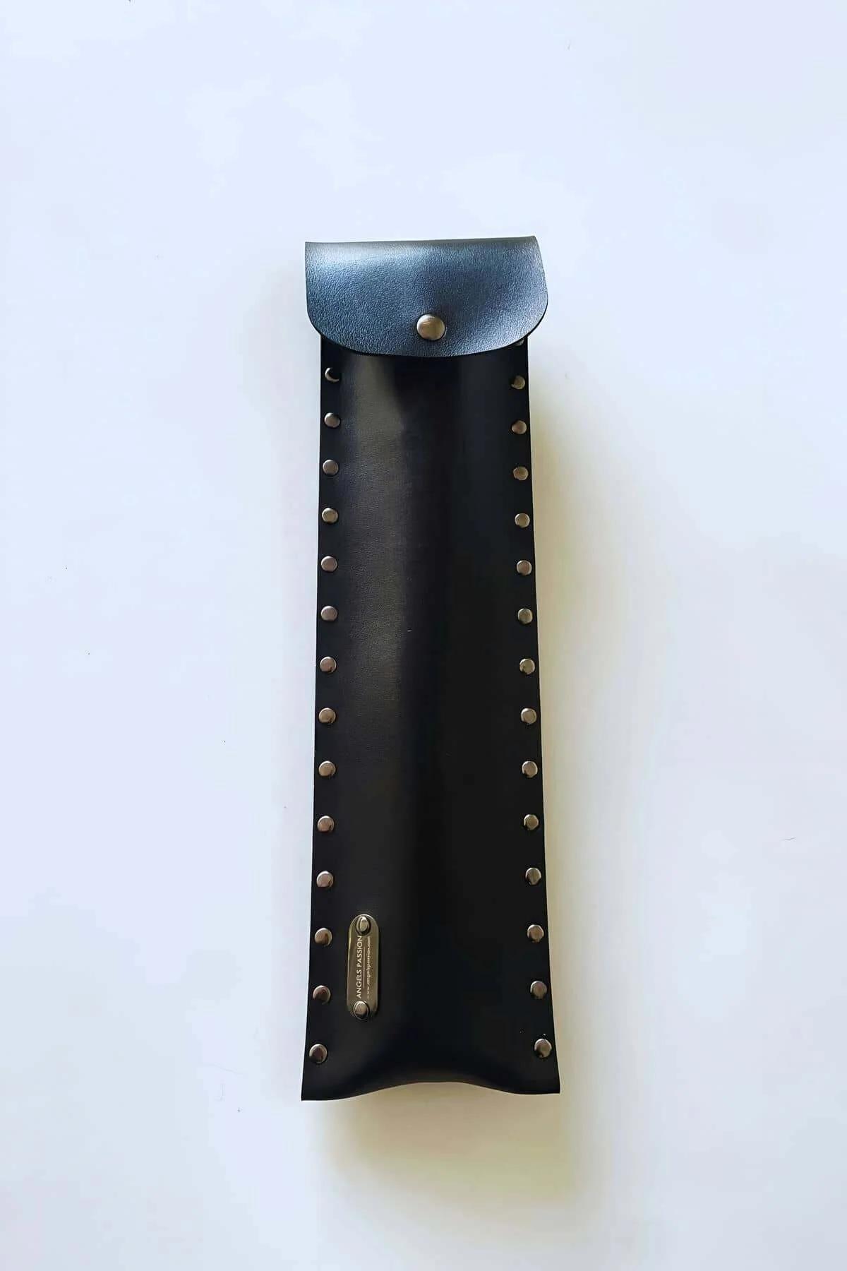 Close-up of double silver stud rows on black PU leather cane pouch surface