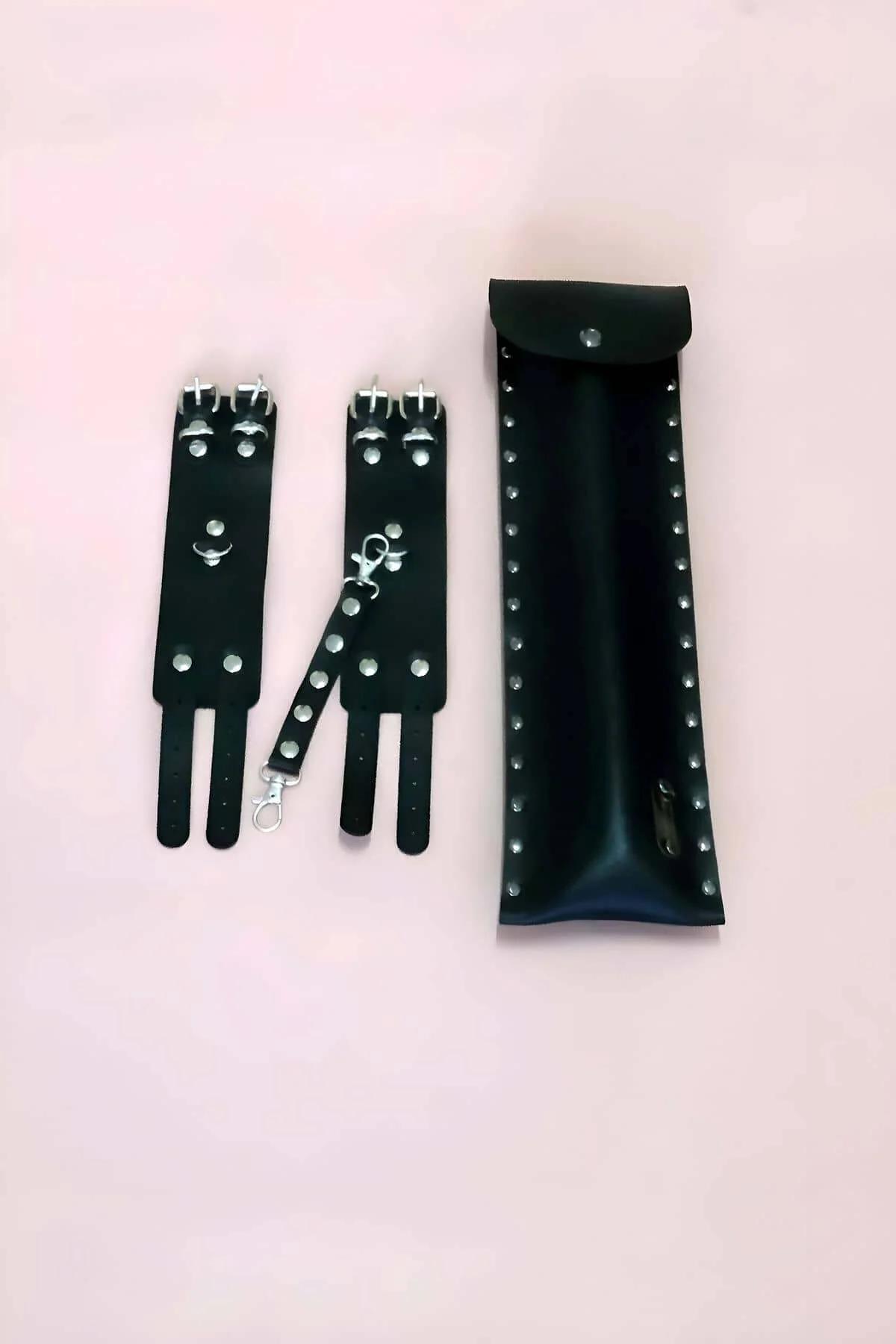 Close-up of black studded vegan leather wrist cuffs with triple straps and lobster-claw connector hardware