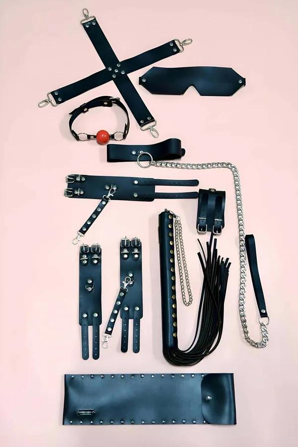 Black faux leather 7-piece restraint accessory set with hogtie bar, cuffs, eye mask, ball gag, collar chain leash, flogger, a