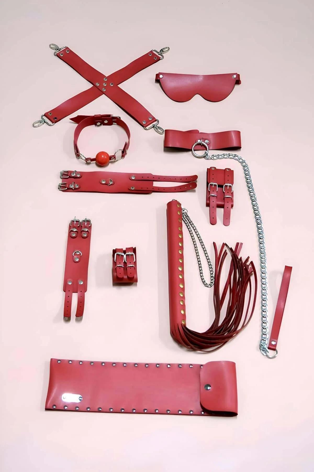 Red faux leather wrist cuffs with double-buckle silver hardware laid flat on white background