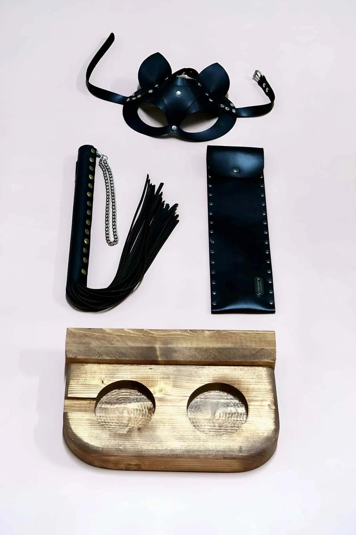 close-up of black PU faux leather handle whip with silver-tone stud trim along edges and chain detail