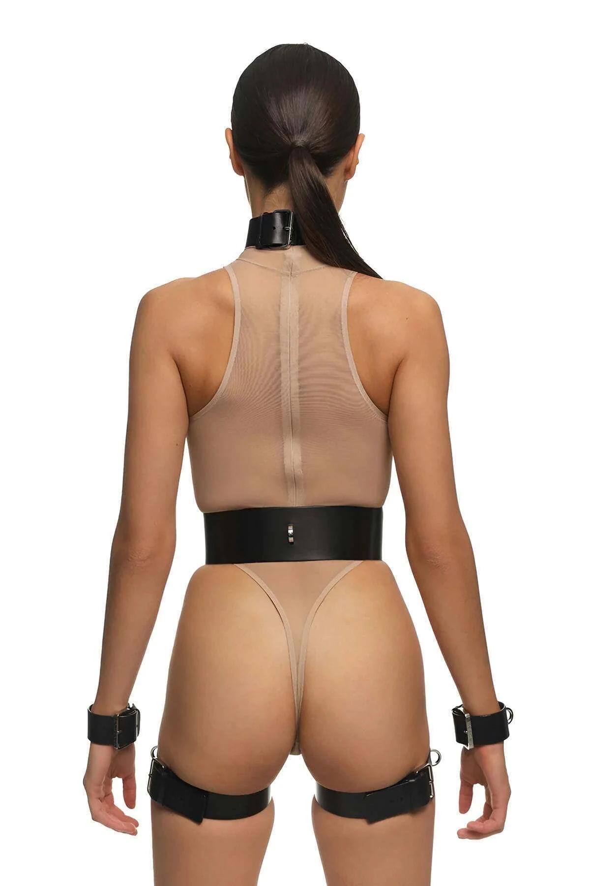 Full body harness set flat lay showing collar, two cuffs, waist belt and garter straps in black vegan leather