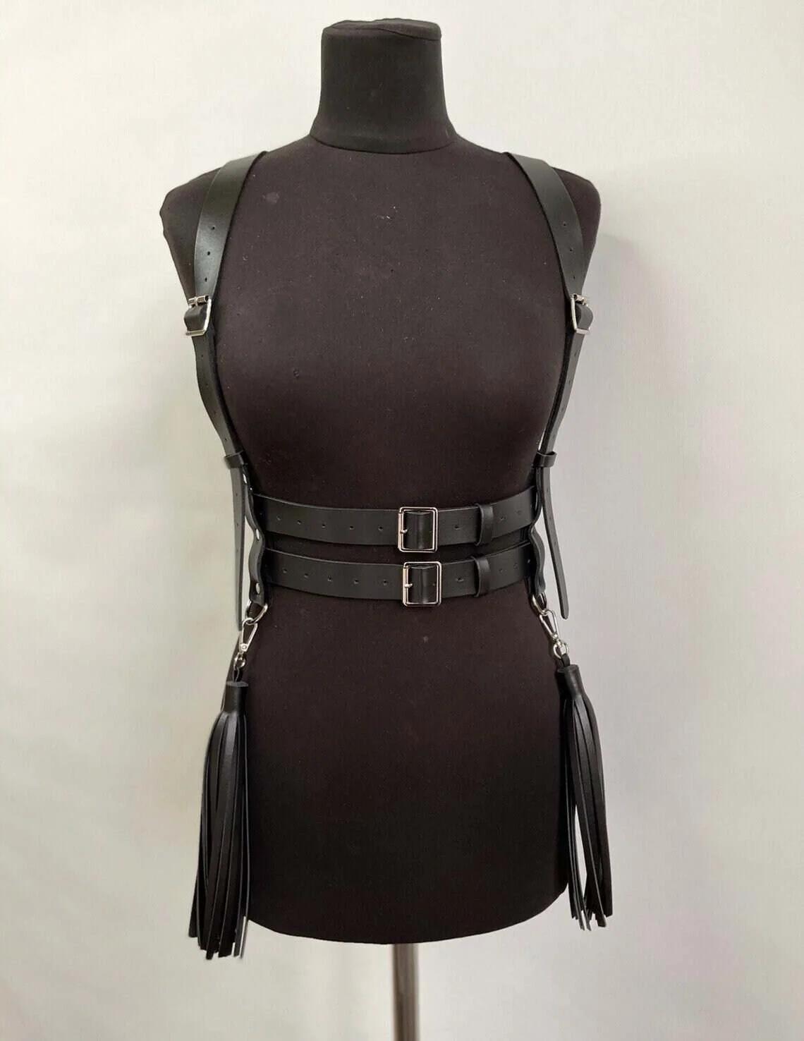 Side detail of faux leather tassel fringe on black body harness attached to silver D-ring at hip