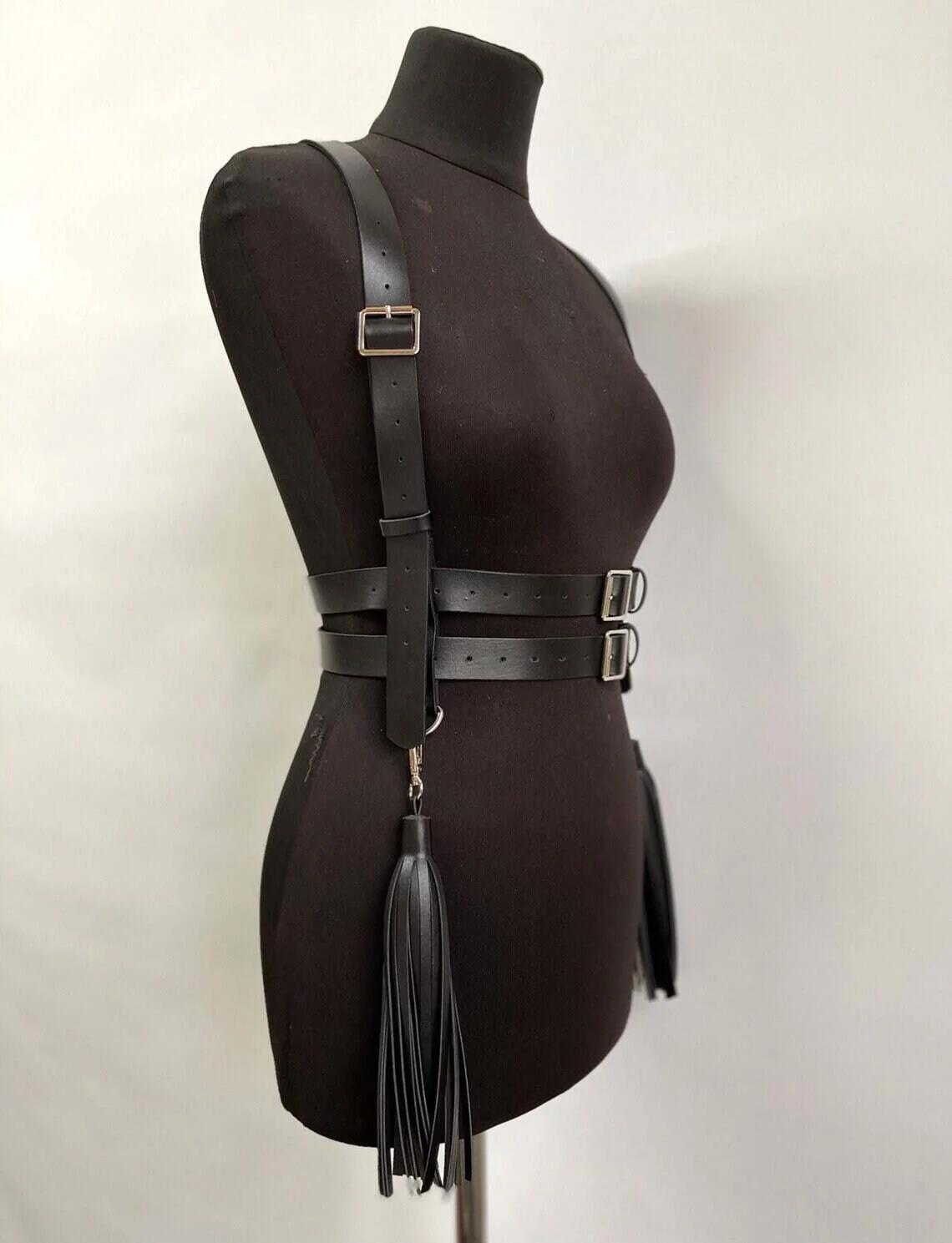 Shoulder strap detail of black strappy faux leather harness with rectangular silver-tone hardware