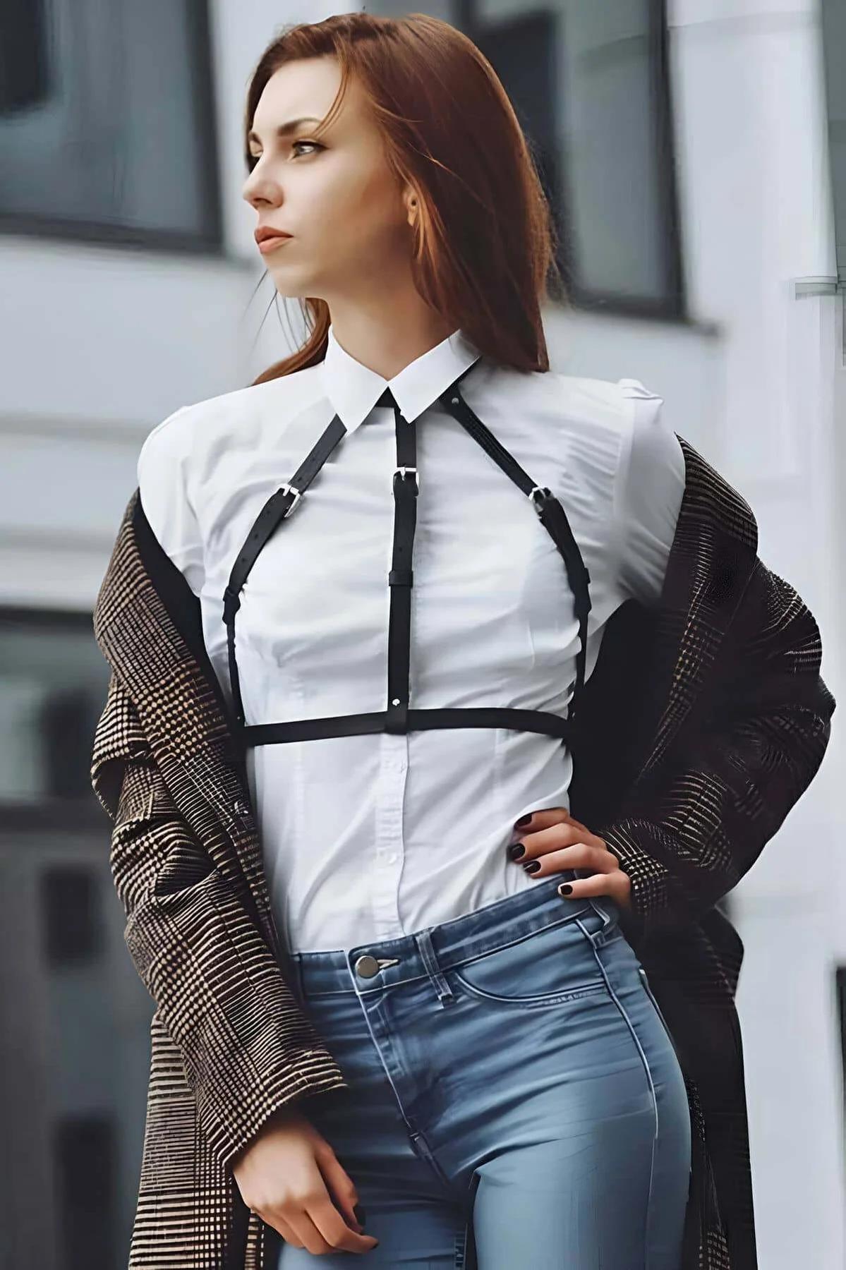 Close-up of silver-tone pin buckle detail on black vegan leather chest harness strap