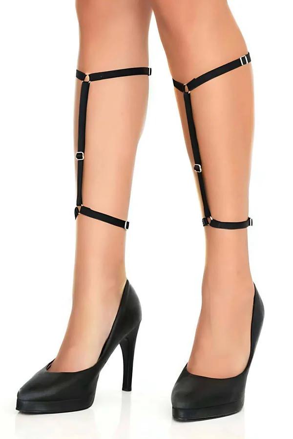 Black strappy leg harness with silver O-rings and buckles wrapping from thigh to ankle over bare skin