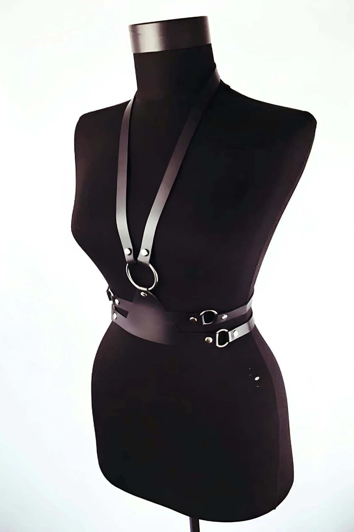 Close-up of silver-tone O-ring and 2 cm wide black faux leather strap on chest harness