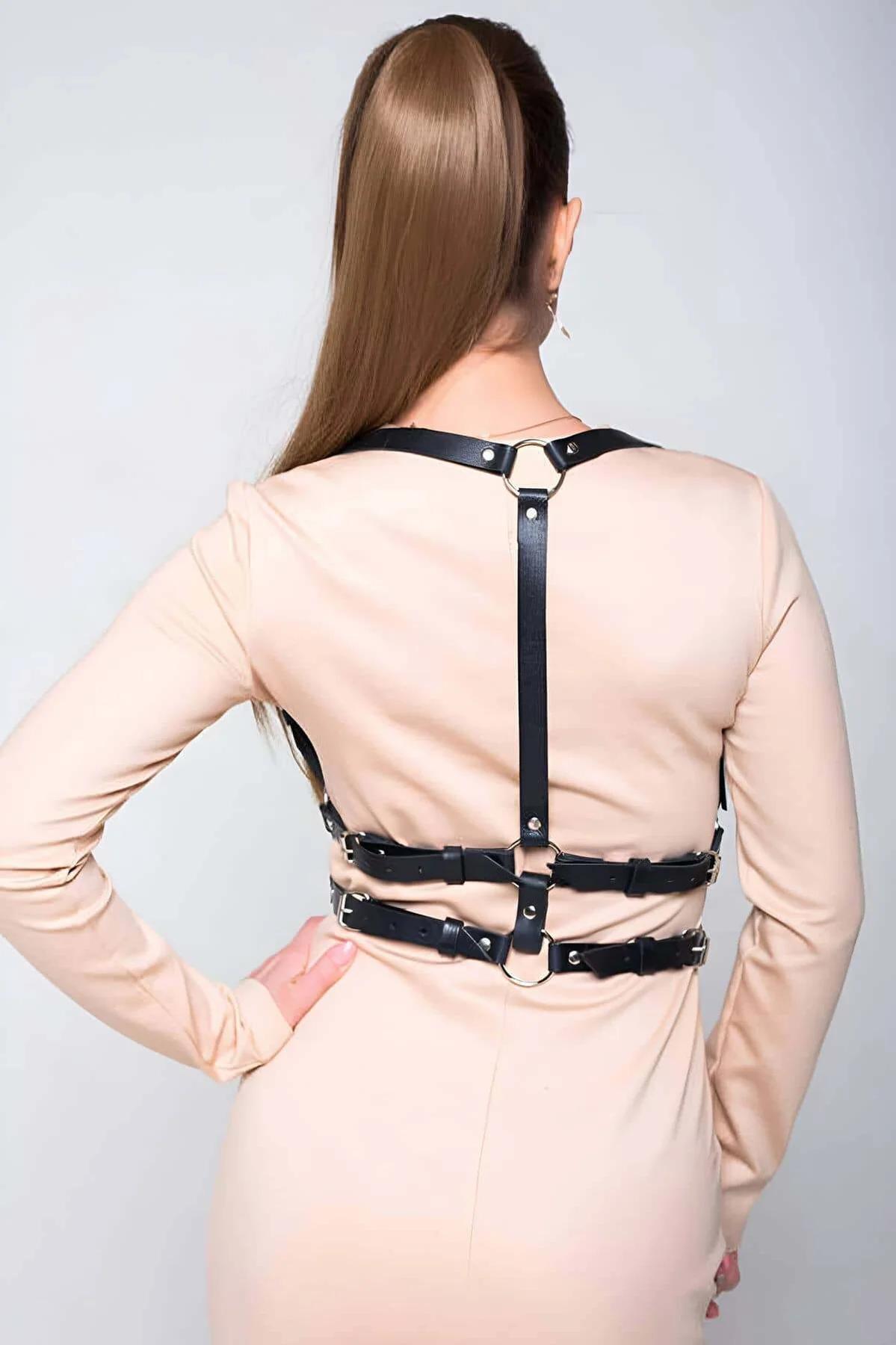 Close-up of gold-tone O-ring junction on black faux leather chest harness straps