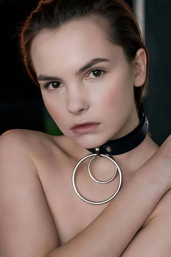 Black faux leather choker collar with two interlocking silver O-rings on model neck close-up