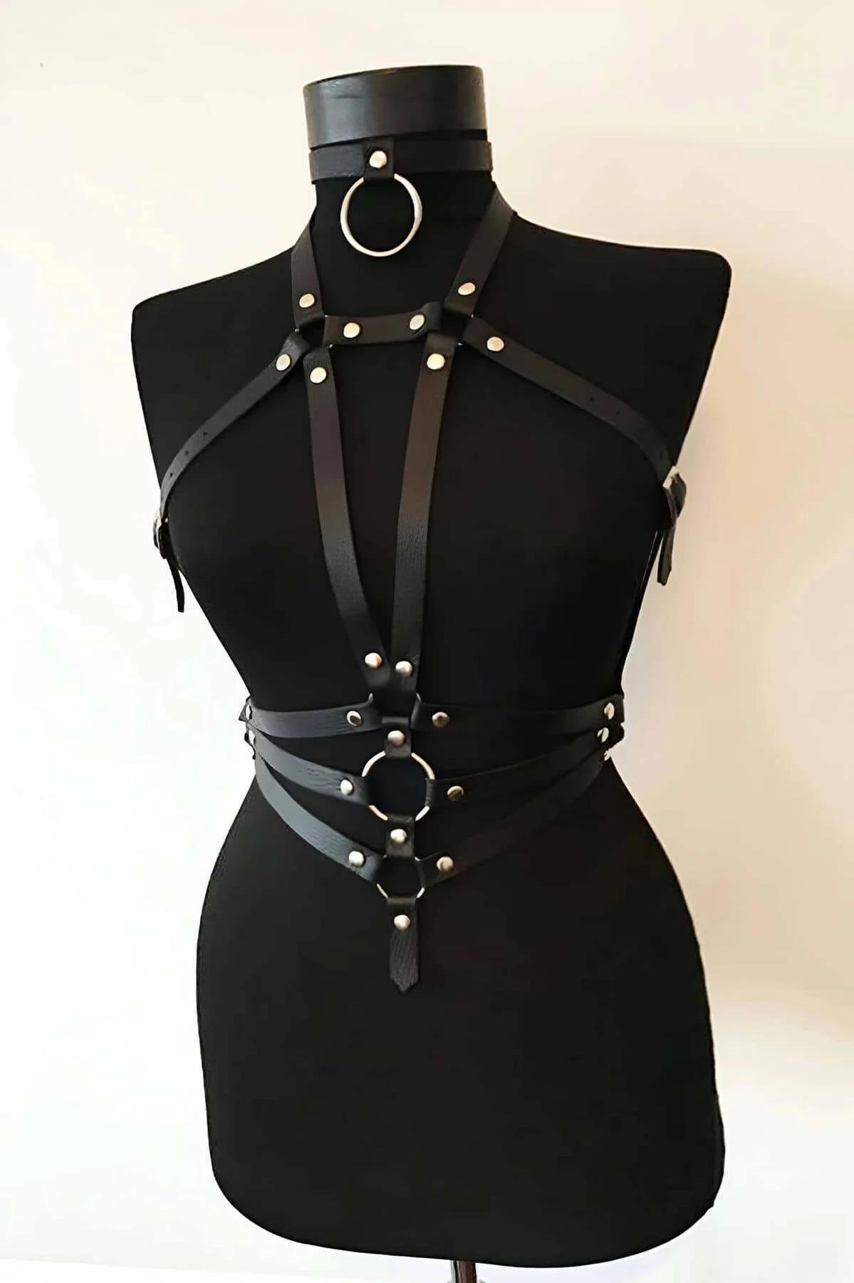Close-up of silver O-ring center anchor and round stud rivets on black faux leather chest harness straps