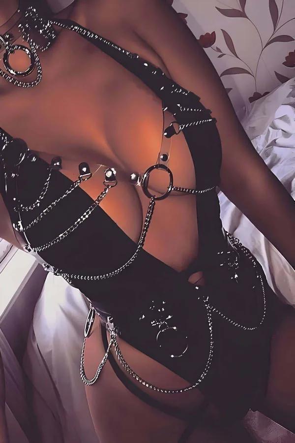 Black faux leather full body harness with draped silver chains, O-rings, and clear PVC straps covering chest to hip