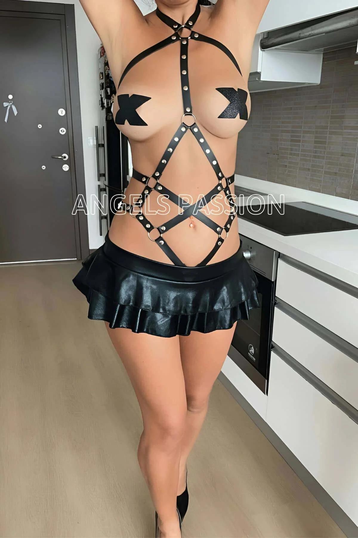 Close-up of silver O-ring and rivet stud detail on black faux leather body harness straps