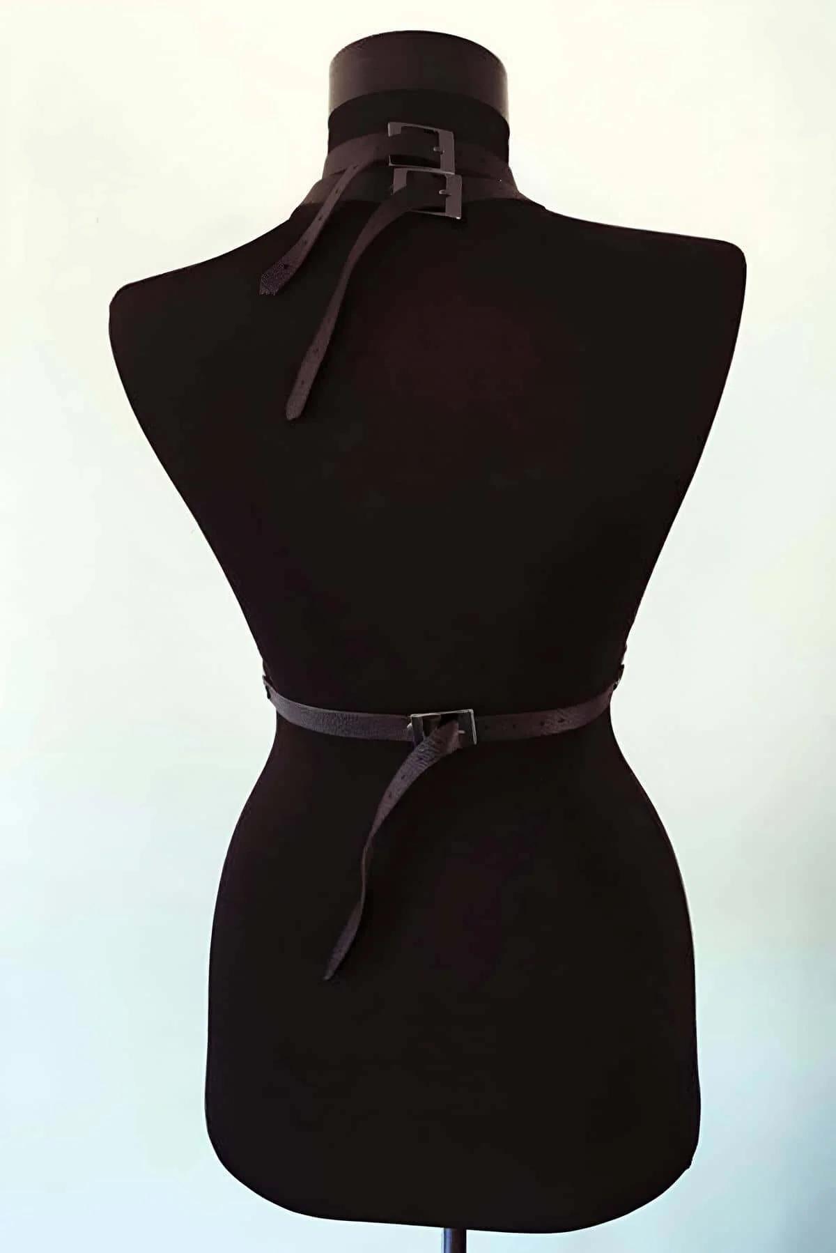 Side view of black pebble-grain faux leather chest harness showing asymmetric crossing strap layout
