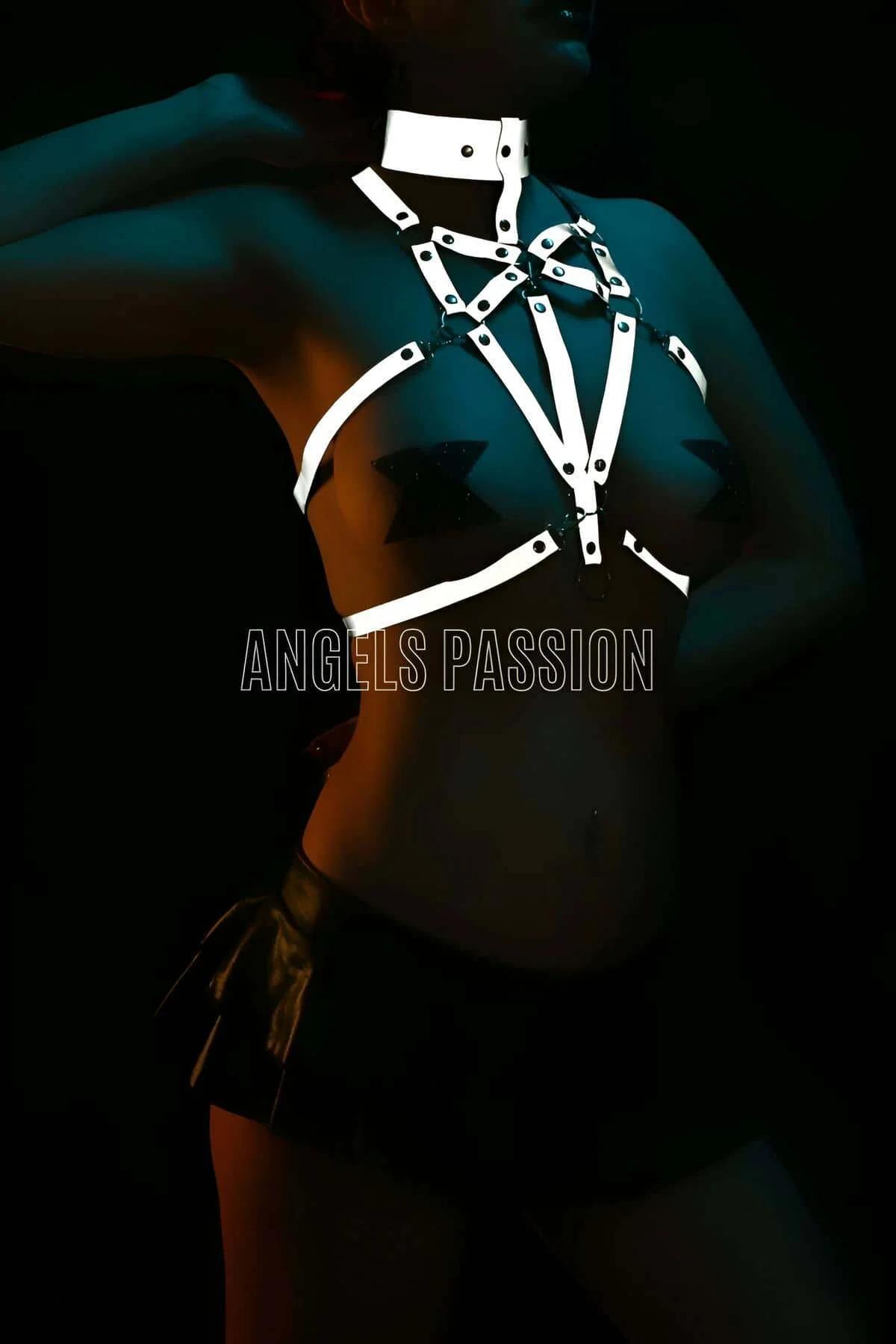 Reflective body harness and wide choker set glowing under dark venue lighting