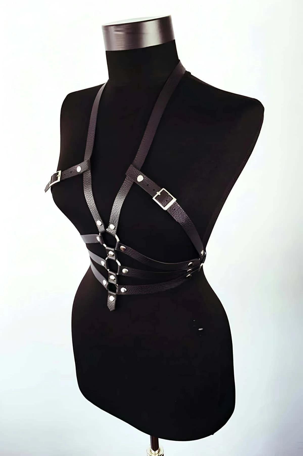 Close-up of silver O-ring and rivet studs on black faux leather chest harness straps