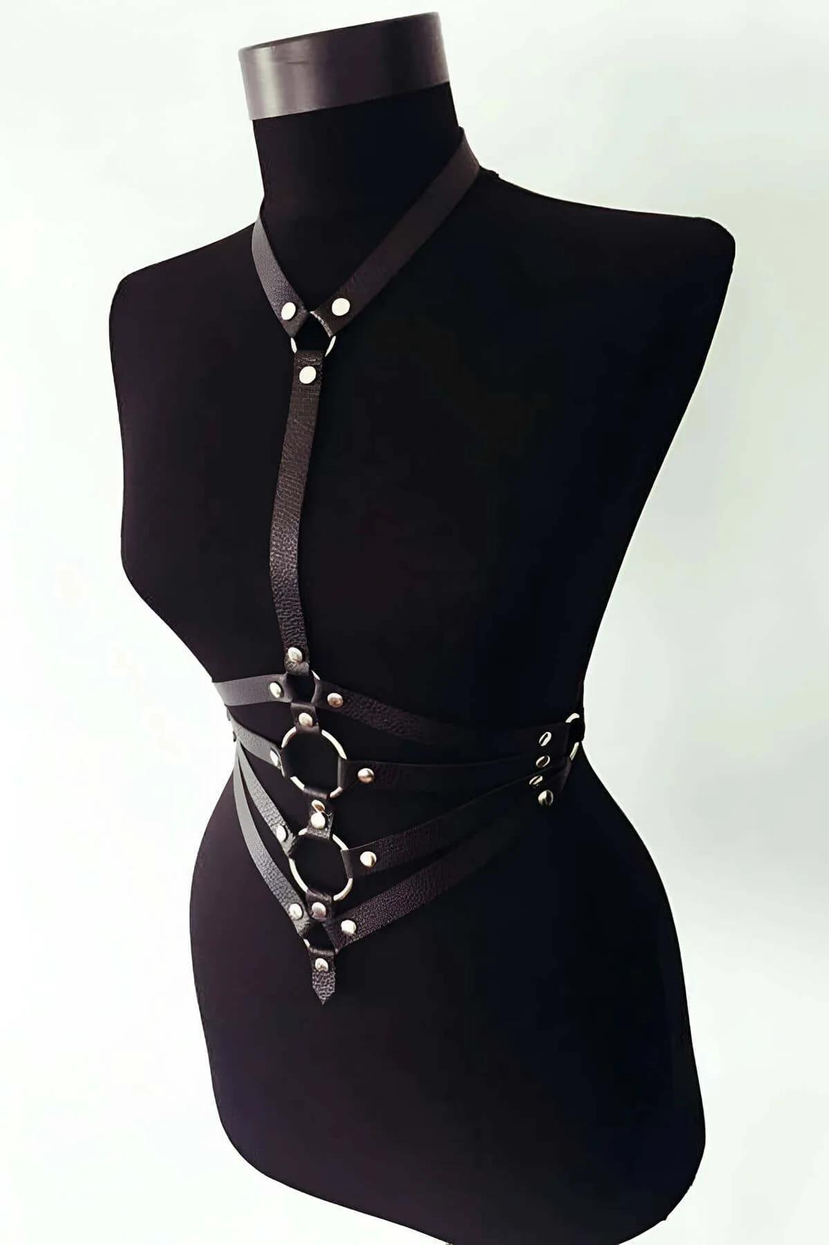 Black faux leather body harness with five stacked octagonal O-rings, silver rivets, collar strap and waist bands on mannequin