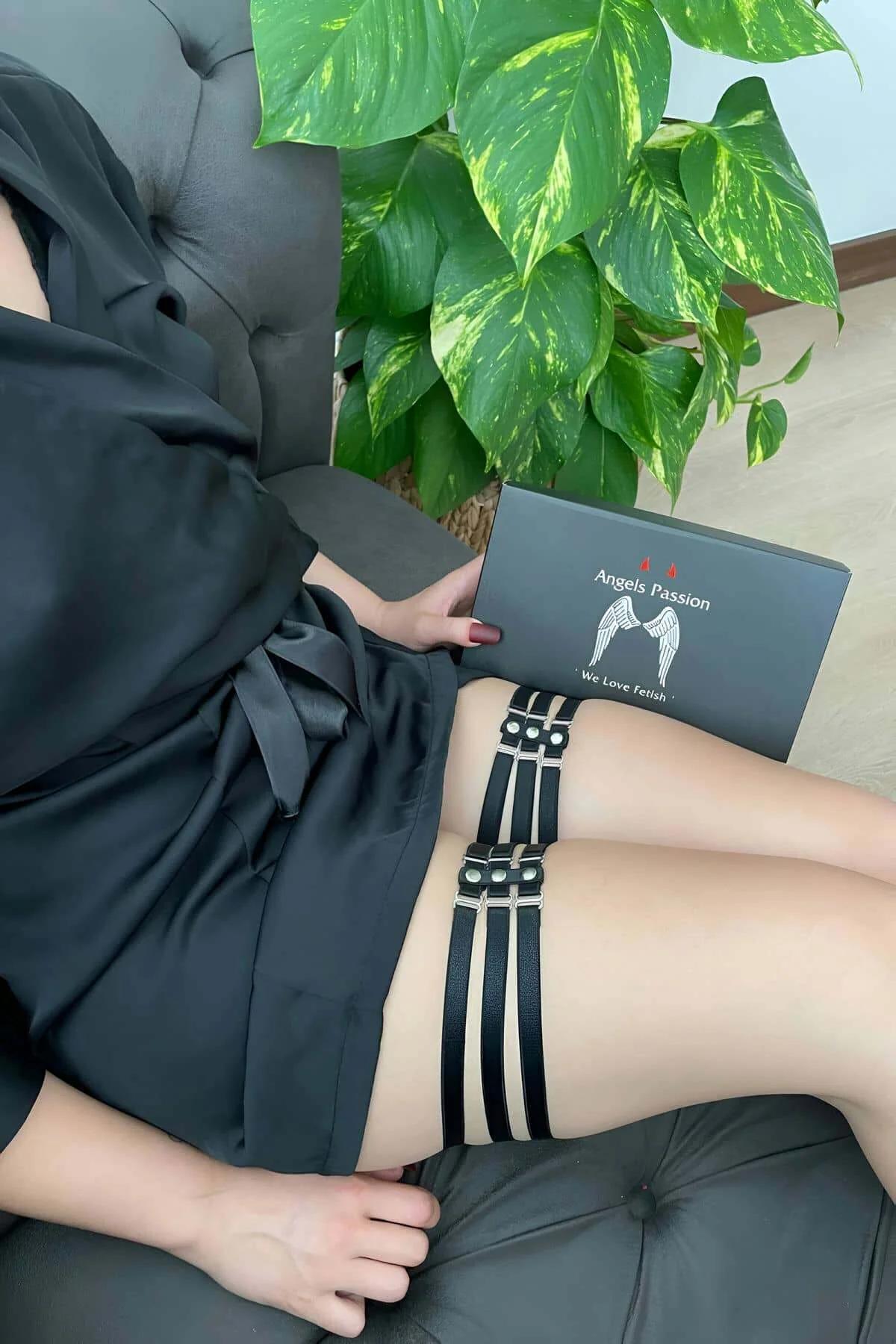 Black multi-strap garter leg harness with silver O-ring rivets worn on upper thigh over bare skin