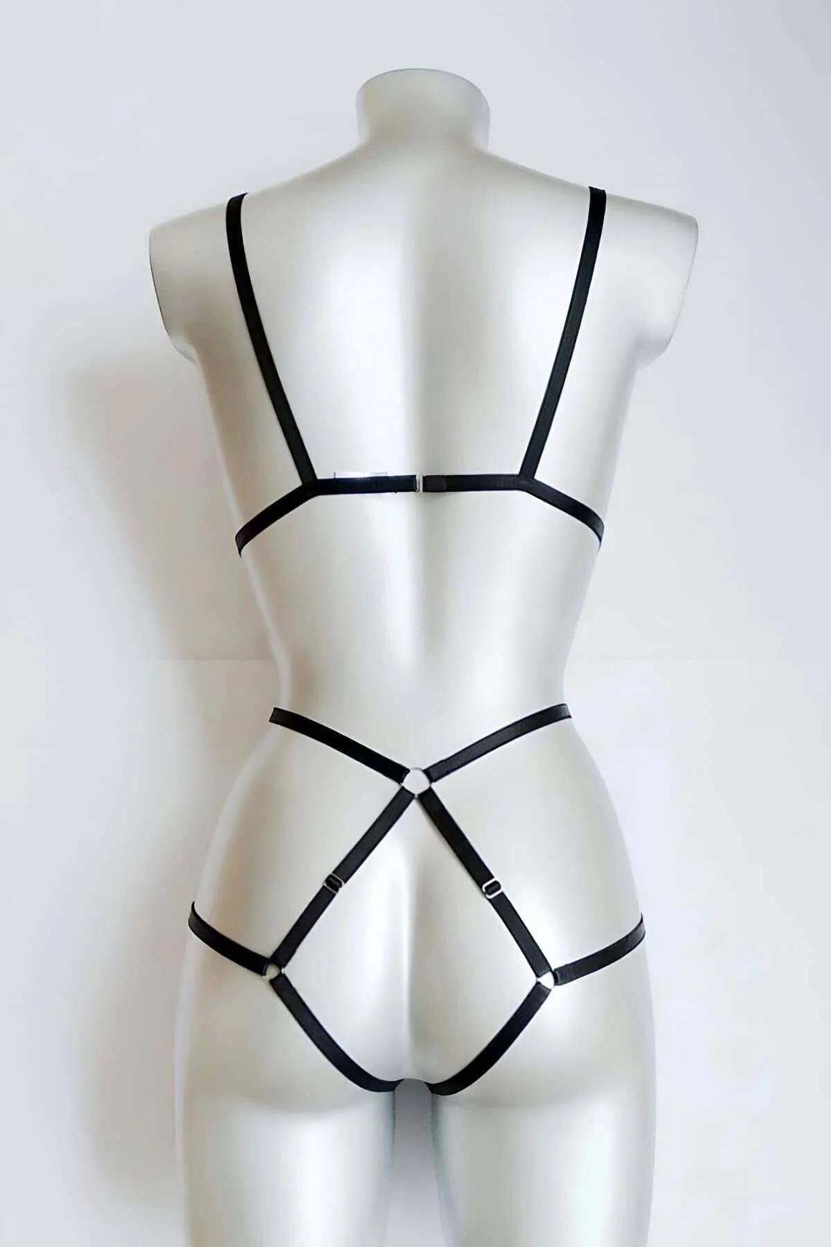 Close-up of silver O-ring accent at chest center on black vegan leather harness straps