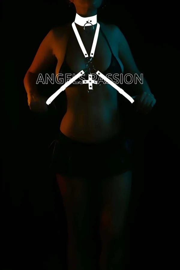 White reflective body harness with wide choker and cross-body X-strap design glowing under dark blue stage lighting