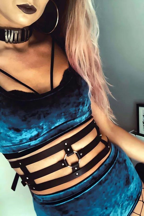 black faux leather strappy waist harness belt with silver studs and O-ring worn over teal velvet top