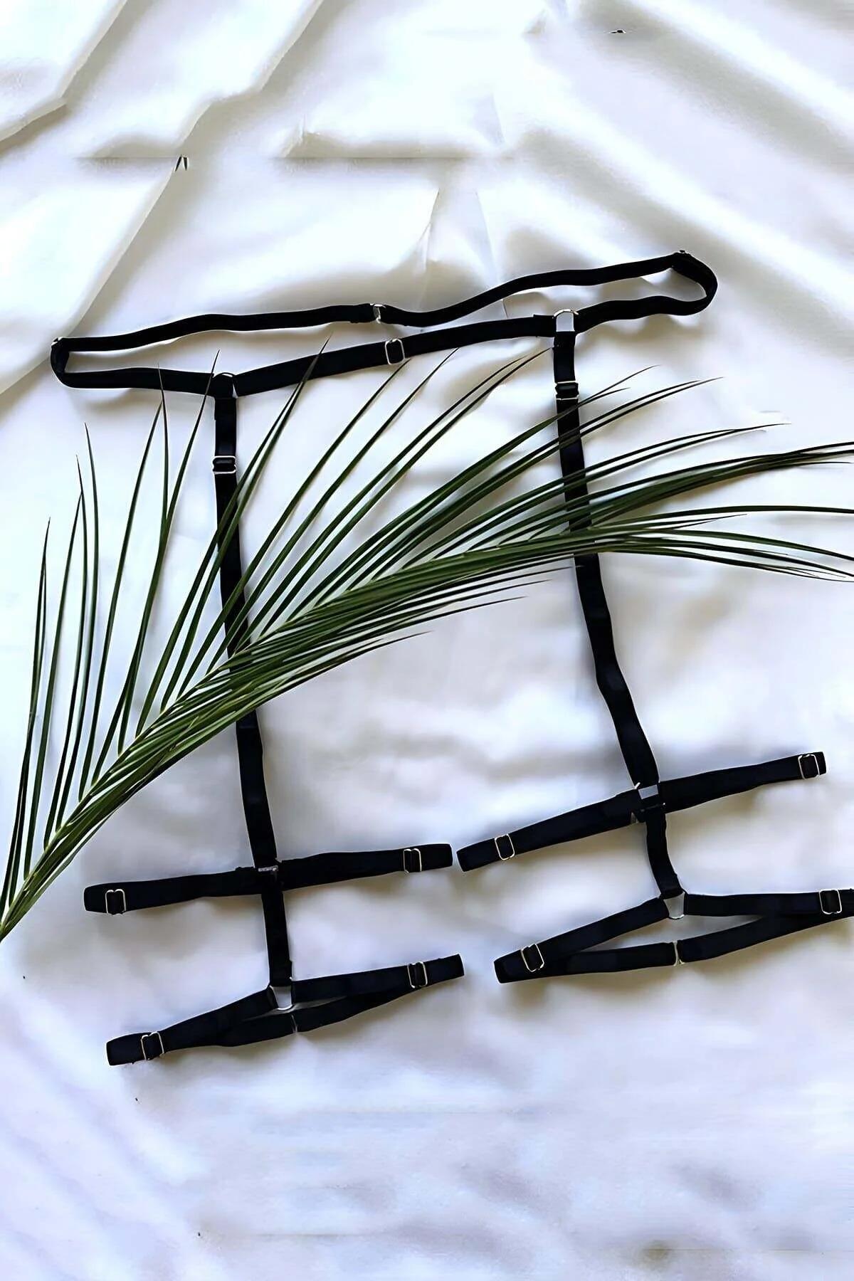 Black elastic strappy leg harness set with silver slider buckles and adjustable waistband laid flat